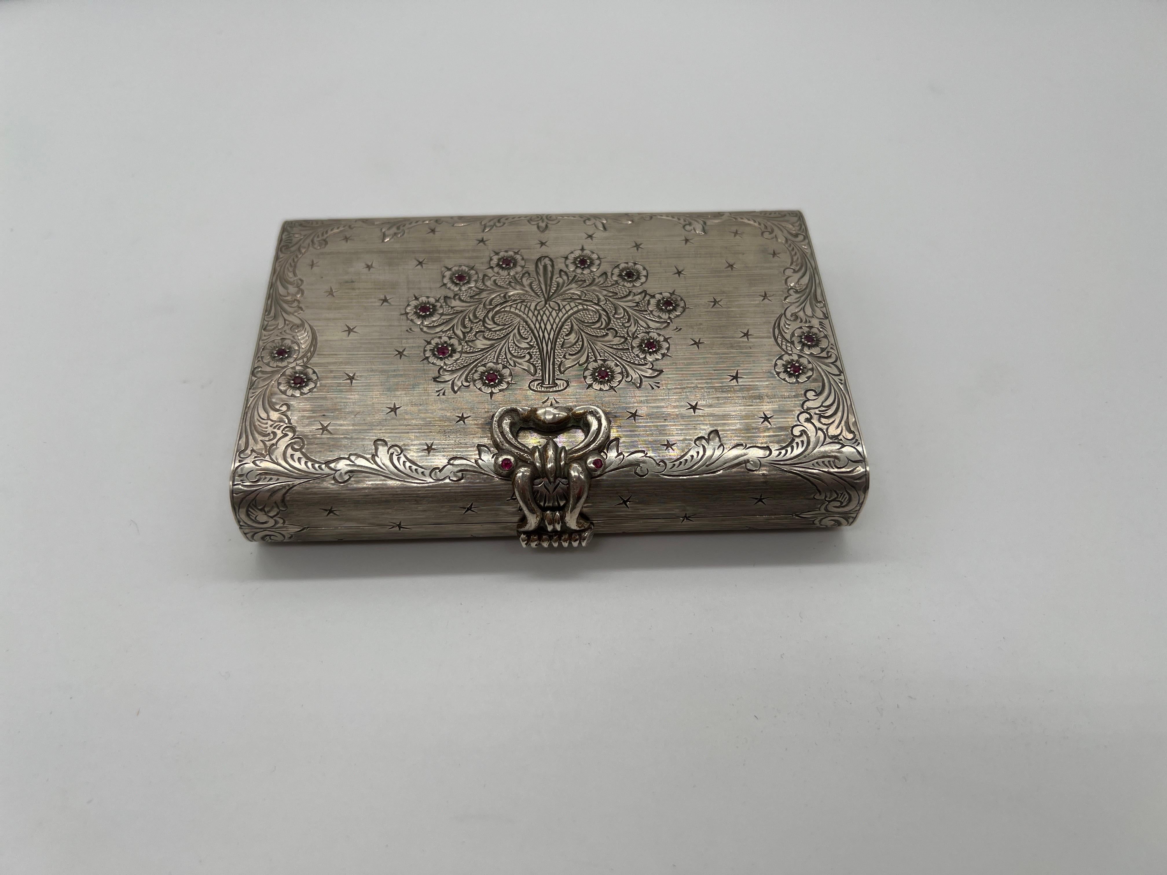Italian, 20th century.

A beautiful Italian 800 silver miniadiere or makeup compact case. The case has rubies inset to the top which accents the hand chased floral decoration. The sides and verso also have fine detail to accent. Interior features a
