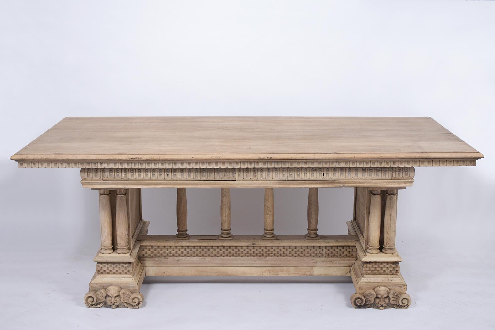 This antique Italian Baroque style dining room table is made out of walnut wood with a newly bleached finish and has been completely restored. This dining table features a large wooden top, detailed carved moldings throughout, and two large top