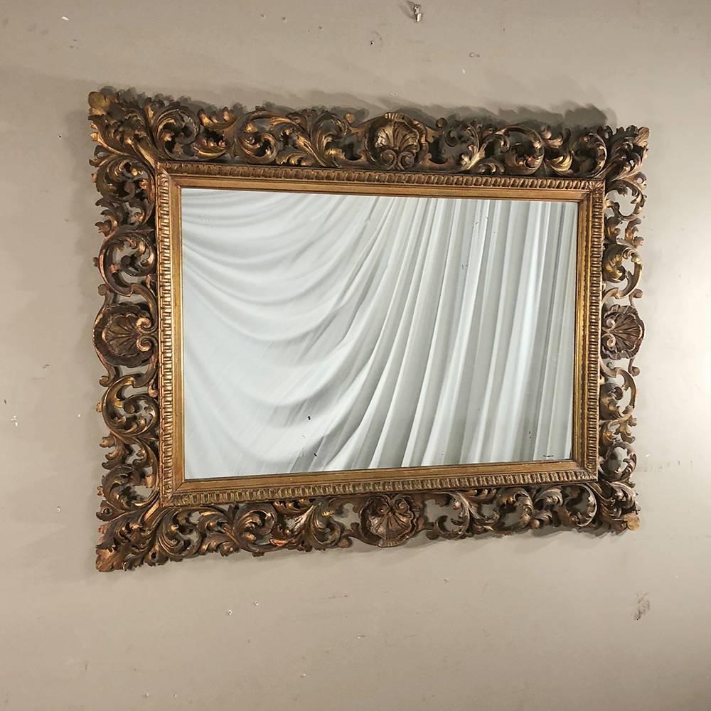 Antique Italian Baroque giltwood hand-carved mirror is a splendid example of the genre, and features a stylish flair that would be welcome in any room! The entire wraparound frame is pierce-carved representing a superlative example of the wood