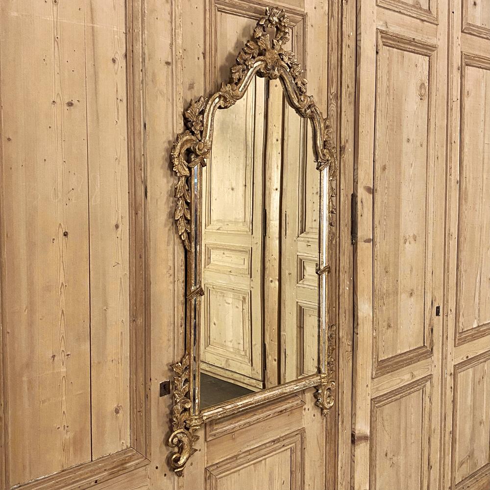Antique Italian Baroque giltwood mirror is a study in the style, executed with amazing Italian flair! The multiple arches of the crown are festooned with floral and foliate motifs, cascading down the scrolled framework to the shoulders which wrap