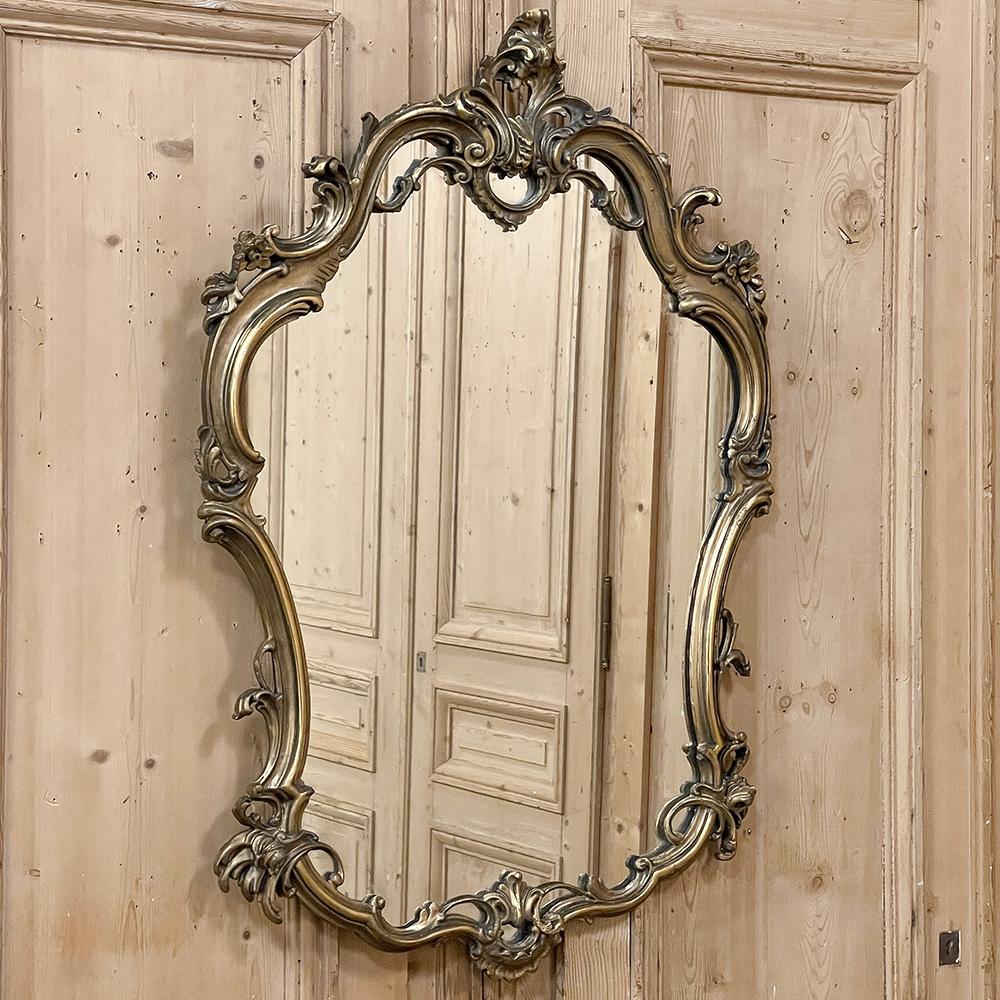 Antique Italian Baroque Patinaed Giltwood Mirror is a marvelous example of the genre, with flowing, naturalistic lines and an exquisitely contoured and scrolled border for a wonderfully intricate effect.  A stylized foliate crest-on-crest appears