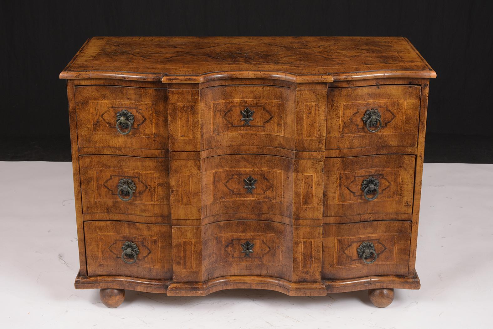 This antique Italian Baroque style commode features a beautiful walnut & burl marquetry veneer design along the top, drawers, and sides. The drawers come with two brass Baroque-style handles, a small accent in the center, and the interior is lined