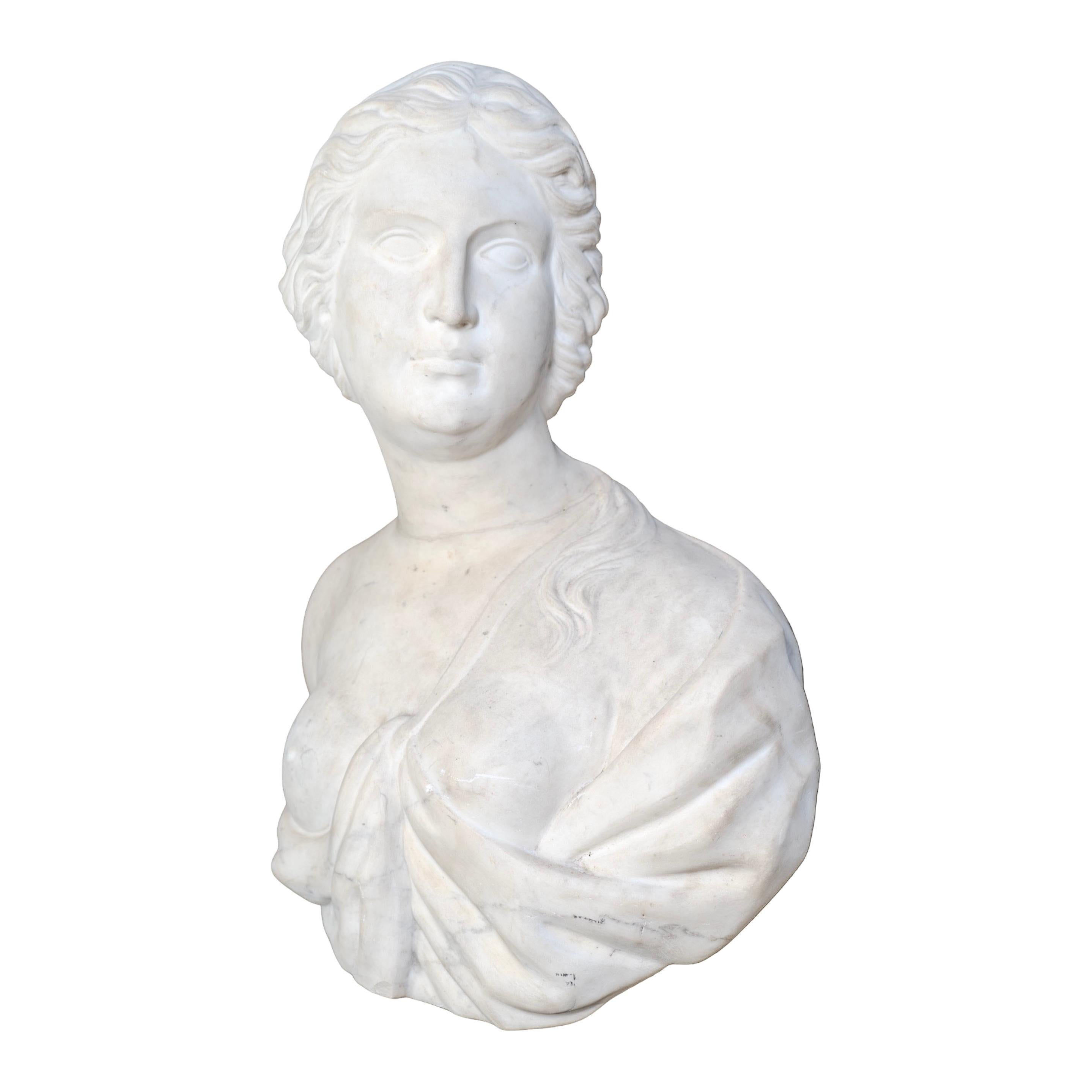 An antique and reclaimed Italian bust, carved in the 19th century from fine Carrara marble. The sculpture depicts a classical female figure, her features softened yet dignified, framed by delicately carved hair pulled back into a low chignon.