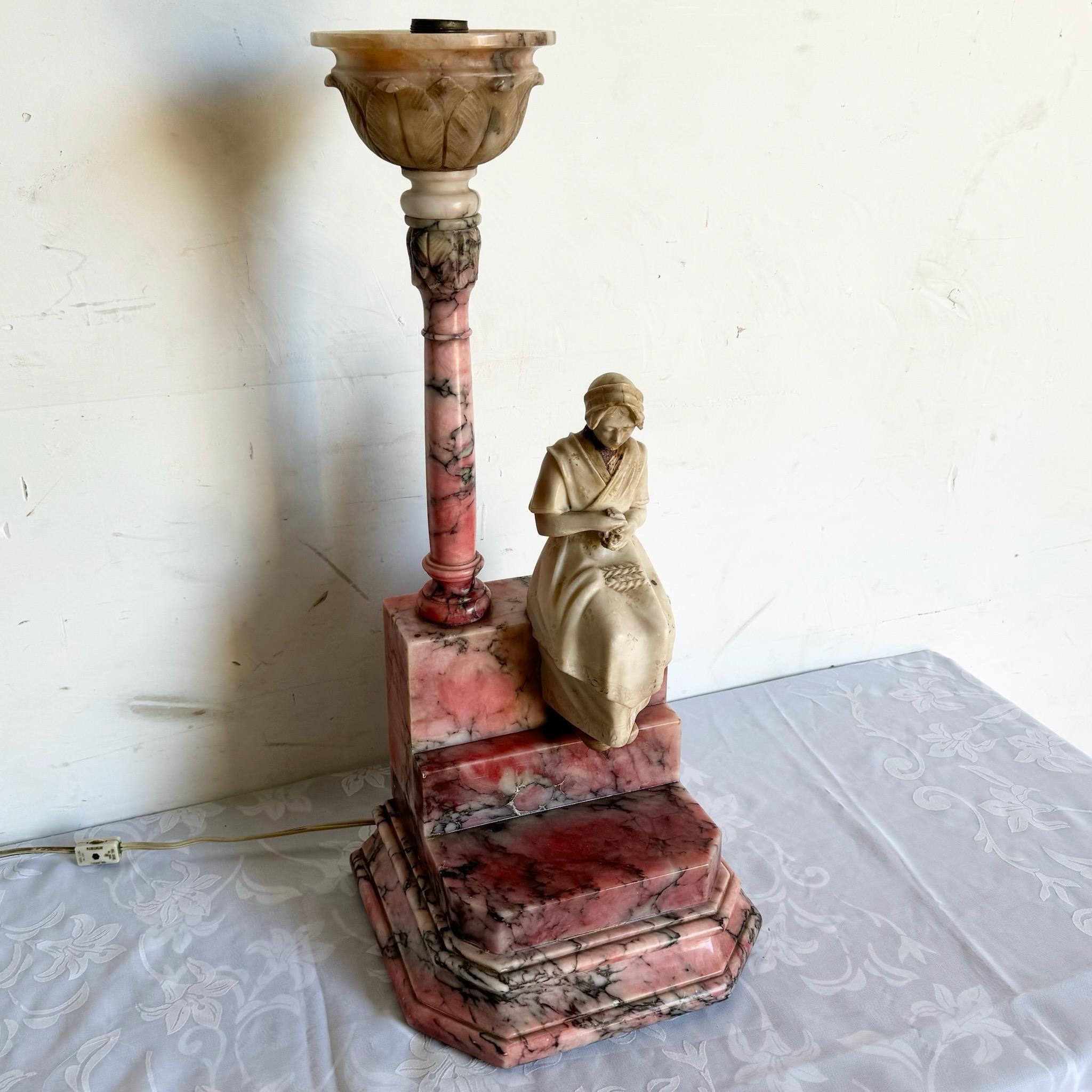 Cette lampe de table italienne antique en albâtre sculpté présente de délicates teintes roses et blanches, créant une lueur douce et élégante. Ses détails finement sculptés et sa base en marbre ajoutent une touche luxueuse, ce qui en fait une pièce