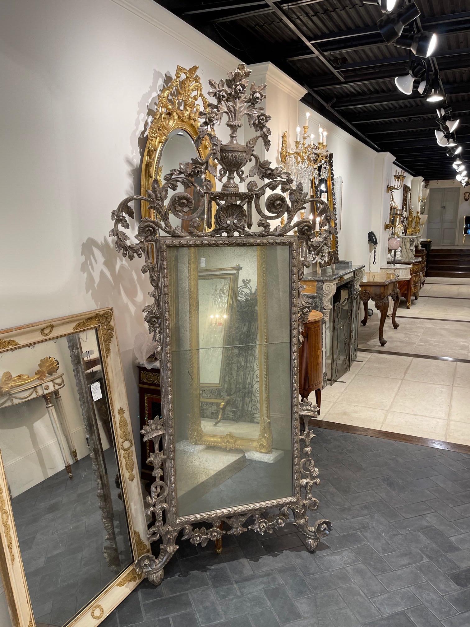 Exquisite antique Italian carved wood silver leaf mirror. Exceptional carving on this piece featuring an overflowing urn with floral images. Very fine quality!!