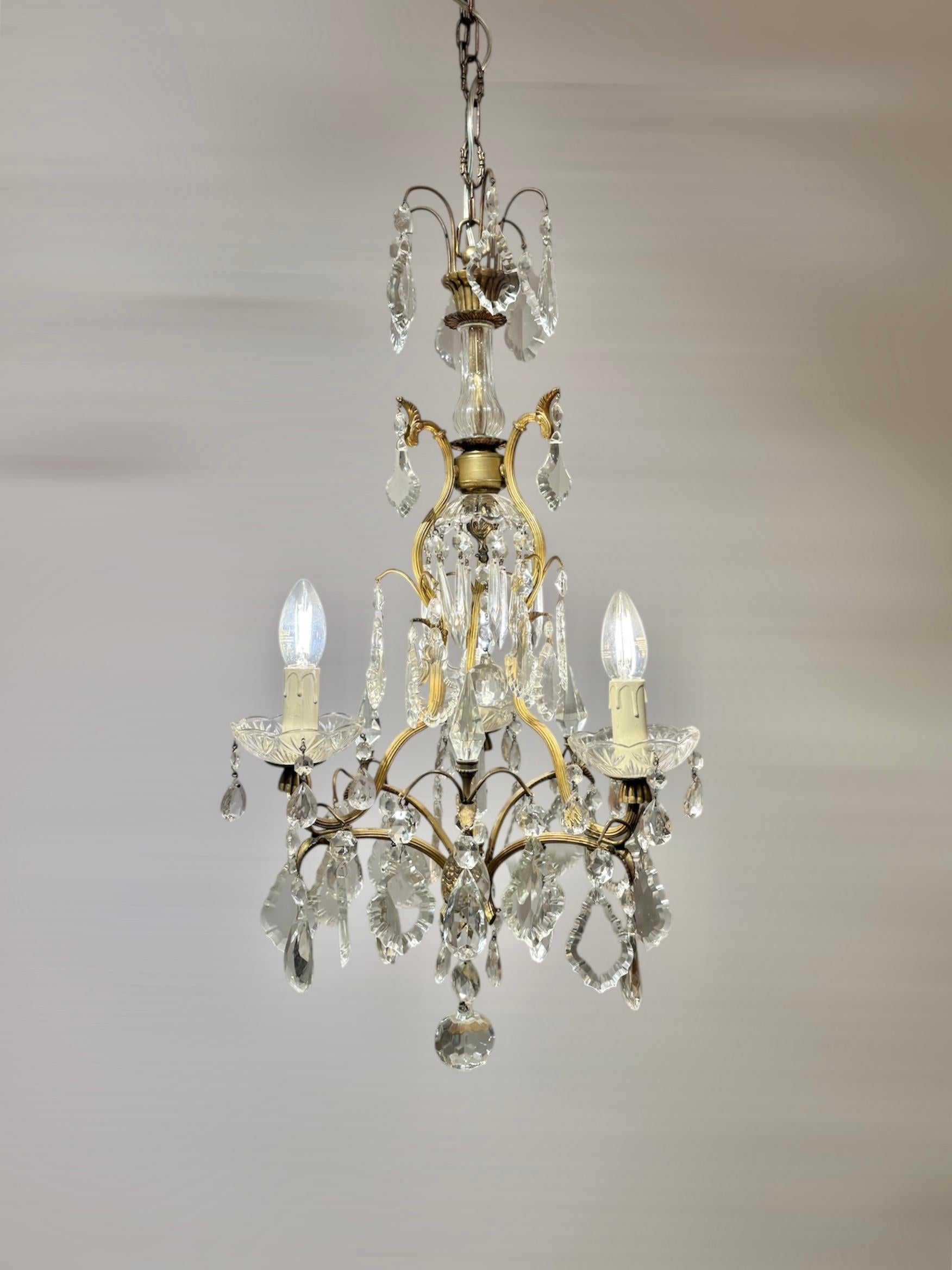 Italian Louis XV Style Gilt Brass and Bohemian Crystal 3-Light Chandelier, 1950s

This charming piece features a finely worked gilt brass frame, richly adorned with hand-cut Bohemian crystal pendants and drops that capture and reflect the light