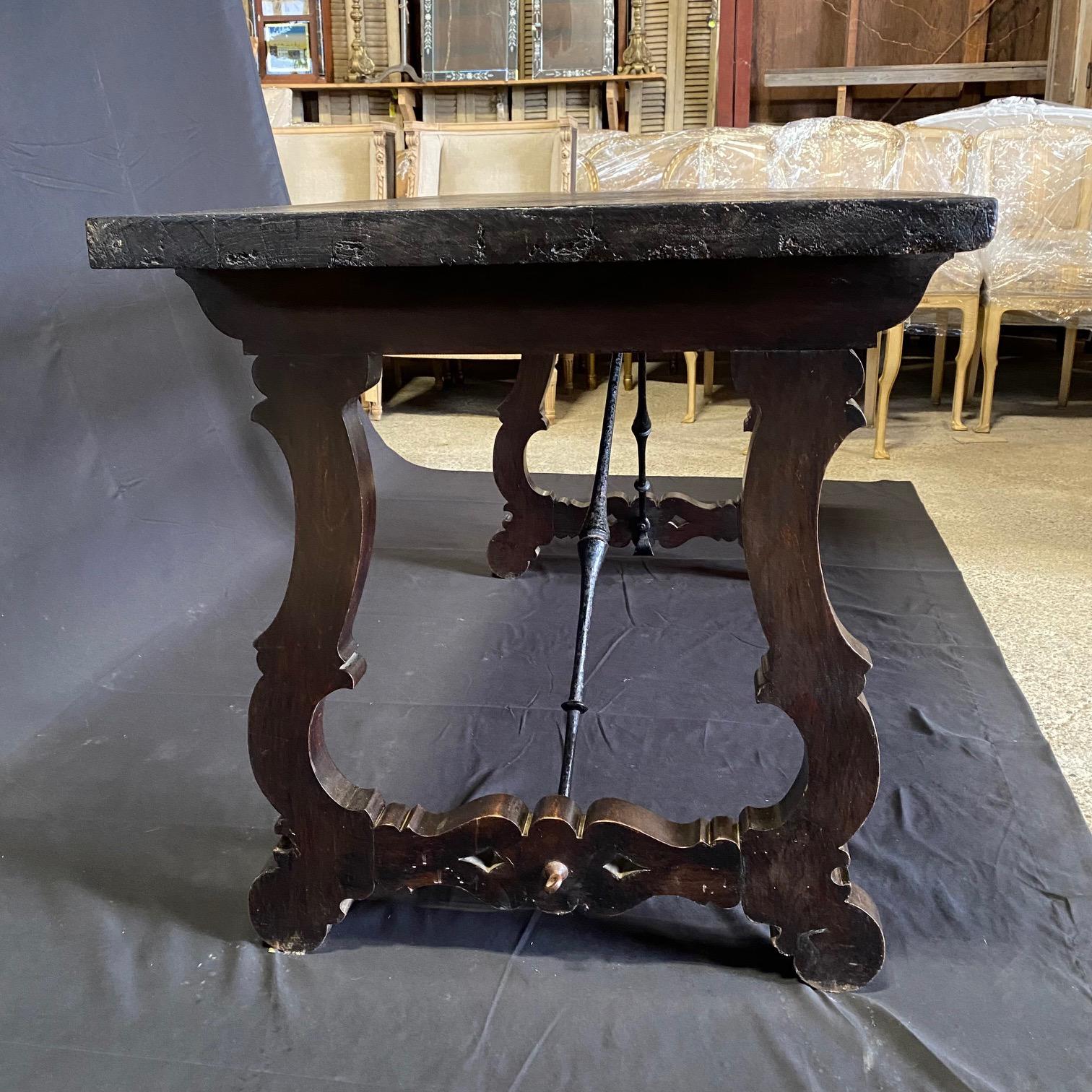 Elegant Italian dining table, console table or writing desk with stunning wrought-iron stretchers in a wonderful size. This ebonized table features a sturdy rectangular top sitting above an exquisite base made of splayed carved lyre legs on either