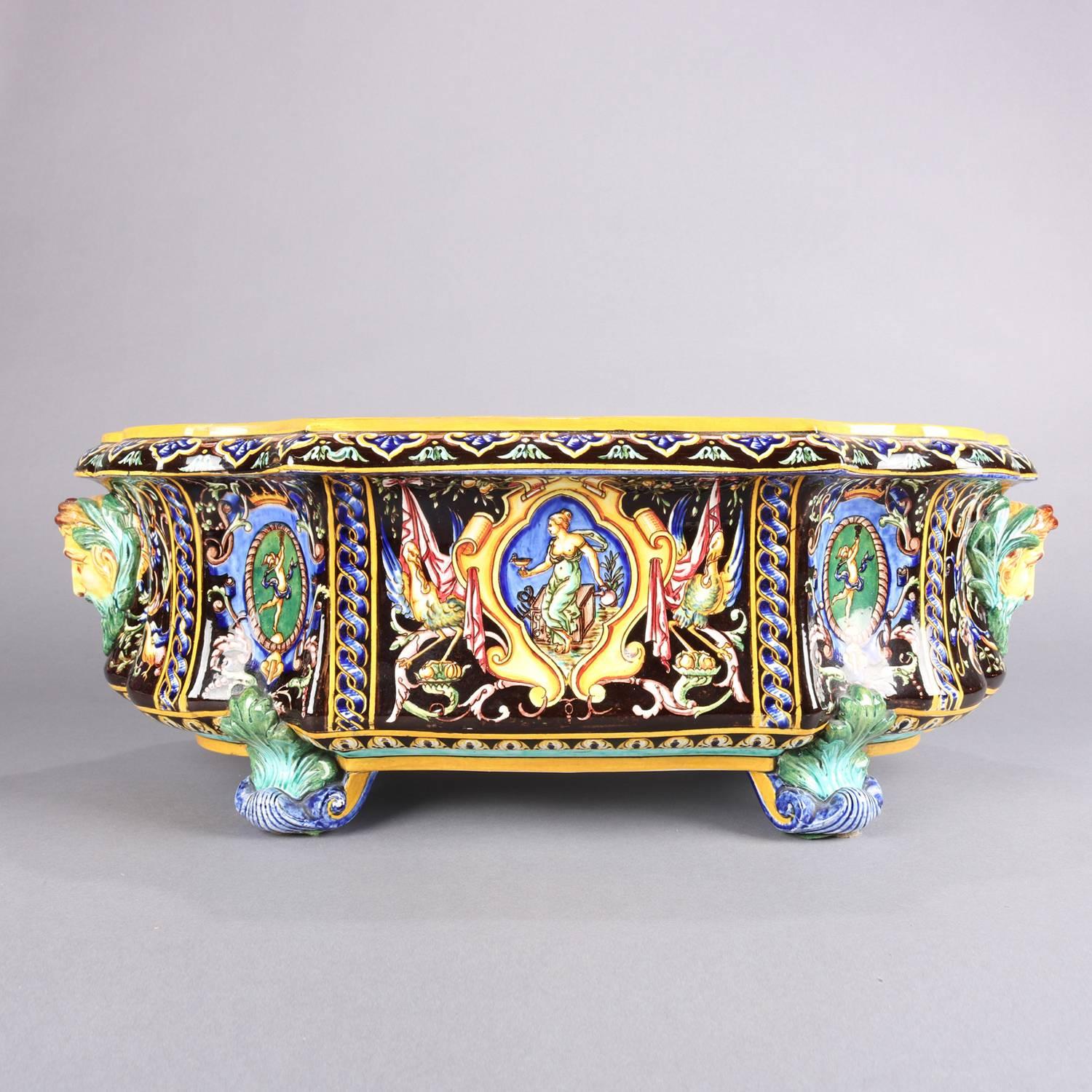 Antique Italian classical hand-painted Faience art pottery planter by Gien features shield or cartouche reserves with partial nude scenes of a woman and bird, applied male masks, raised on scroll and foliate form feet, marked on base with castle