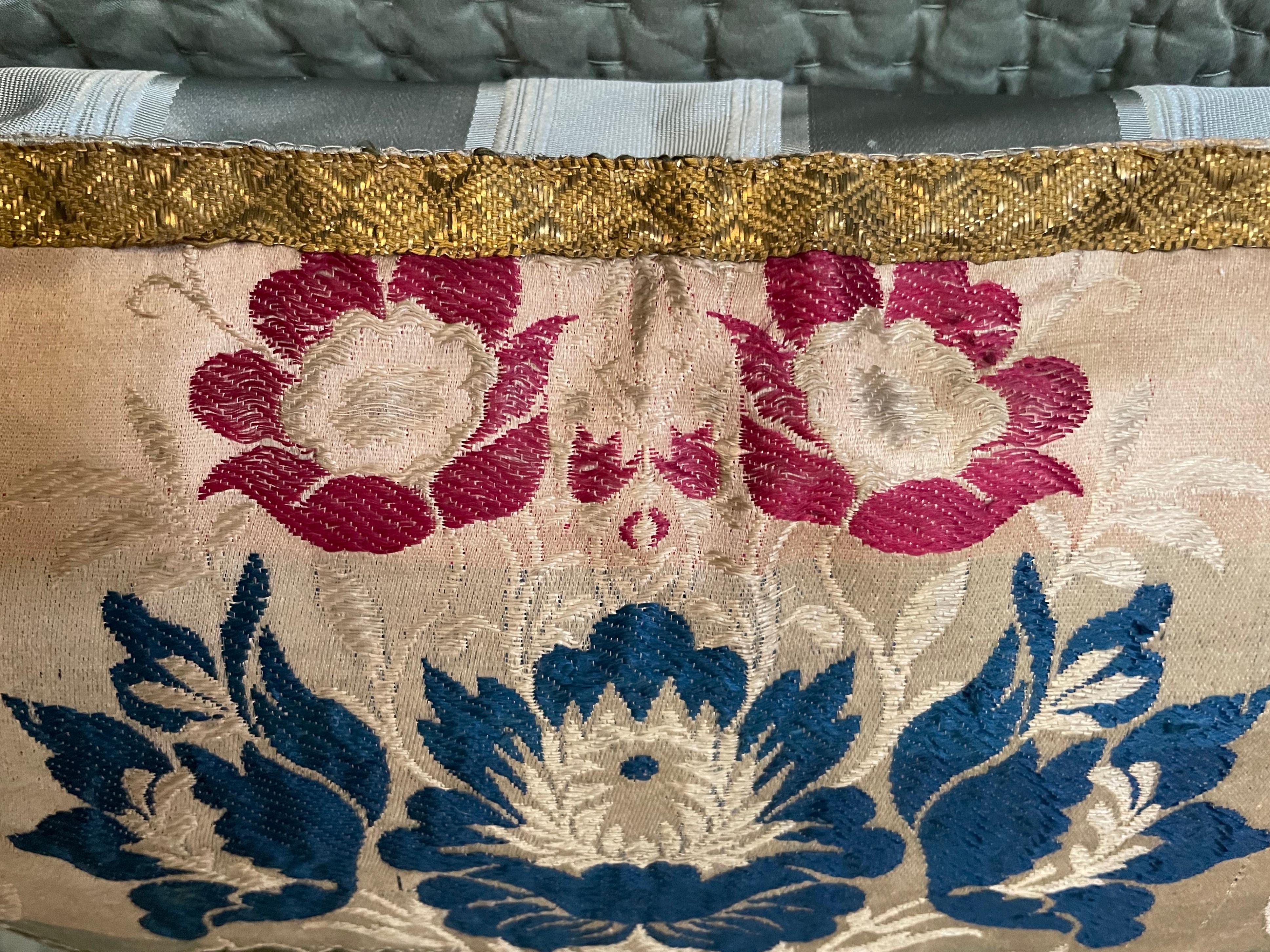 Antique Italian floral pillow.  Continental damascened floral pillow with central decorative moss green urn issuing blue and magenta flowers; antique Italian gilt applied banding at border with antique satin stripe on reverse bordered in antique