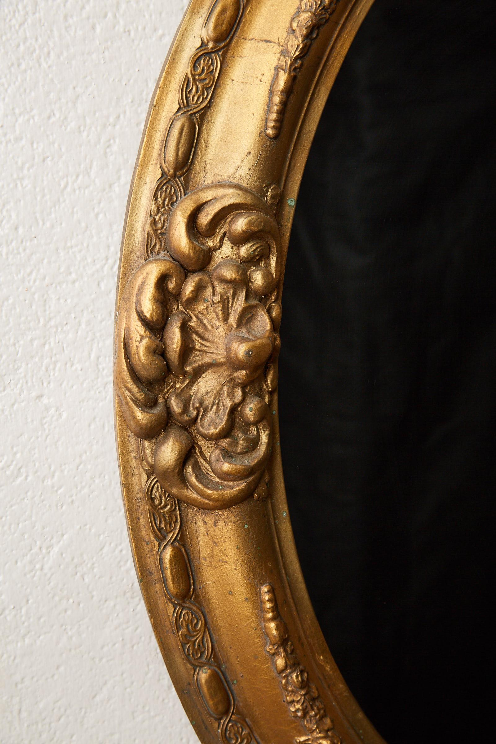 Early 20th century Italian Florentine oval gilt wall mirror with cartouches and details in the Rococo style.