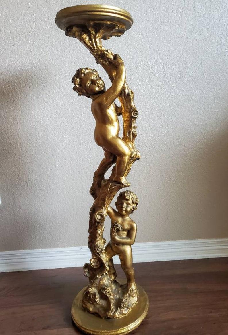 A hand carved antique Italian gilded putti decorated pedestal table or stand. Exquisitely handcrafted in the early 20th century, having a circular top, raised by a pair of robust putti, climbing a highly ornate notched tree trunk.

With wonderful
