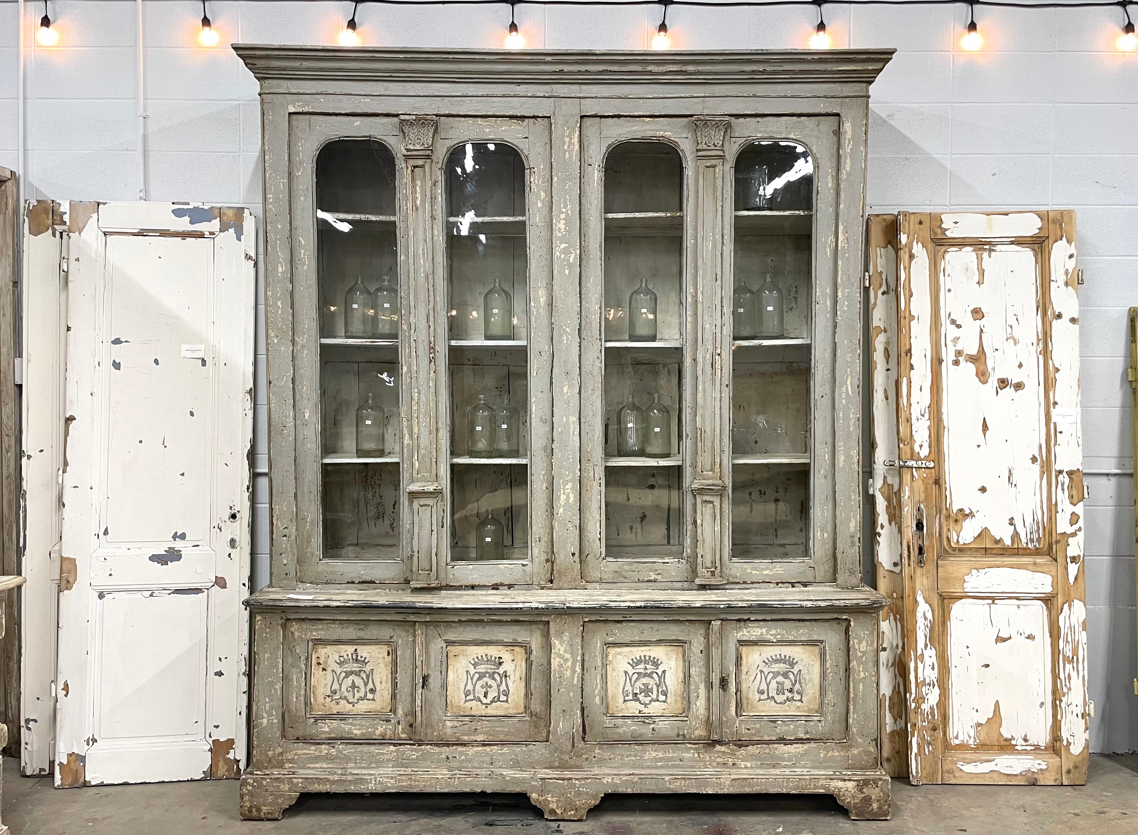 Beautiful substantial late 18th century Italian walnut cabinet or bookcase. The double pair of arched glazed doors with their original wavy glass sits above a pair of double cabinet doors.

The lovely distressed painted finish is likely to be a