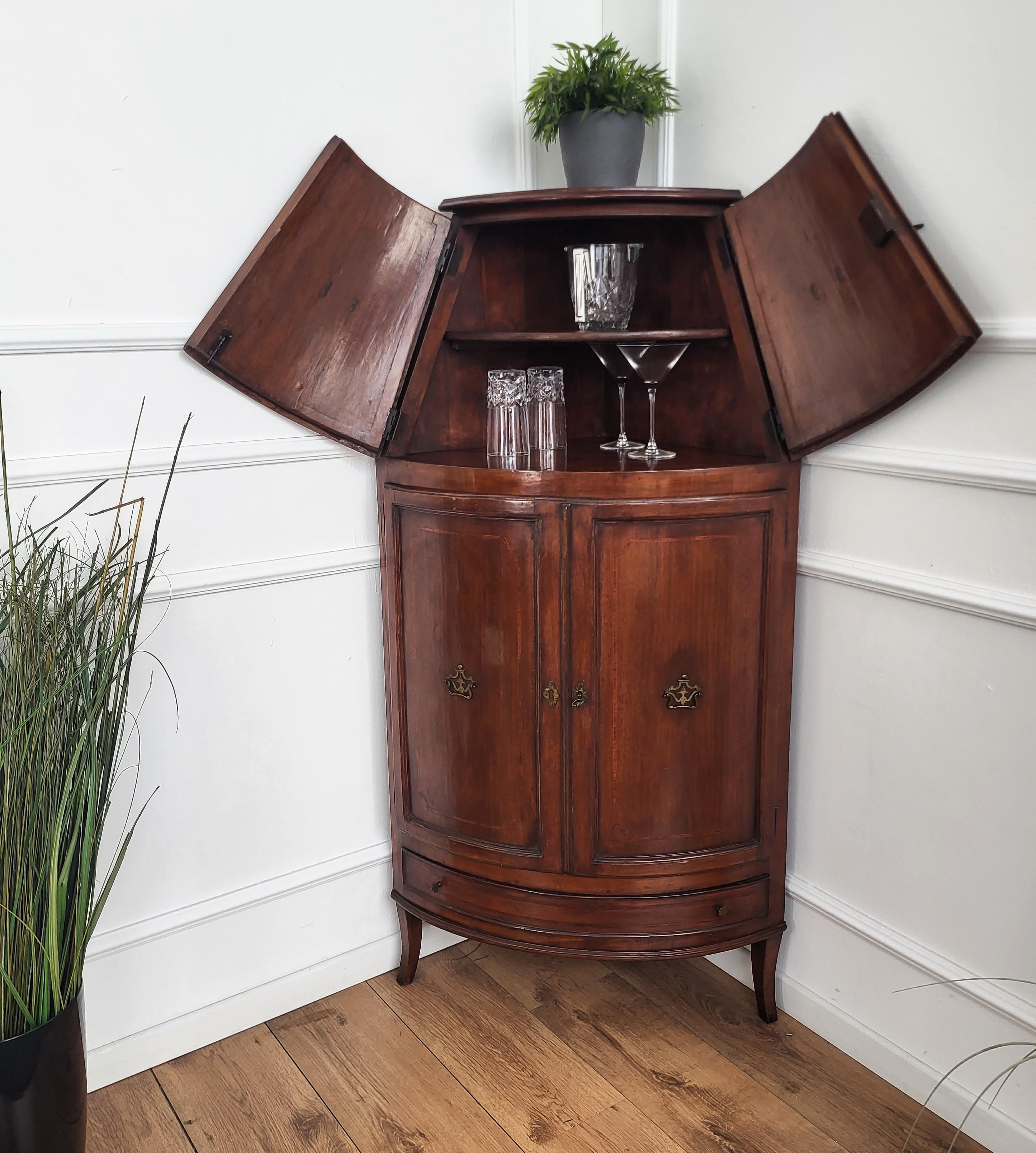 Beautiful and elegant Italian corner cabinet in walnut wood, with great decorative use of the veneer and geometric inlay decors on the top and central two doors and bottom drawer, completed by nice antique brass door handles and keylocks. 

.
