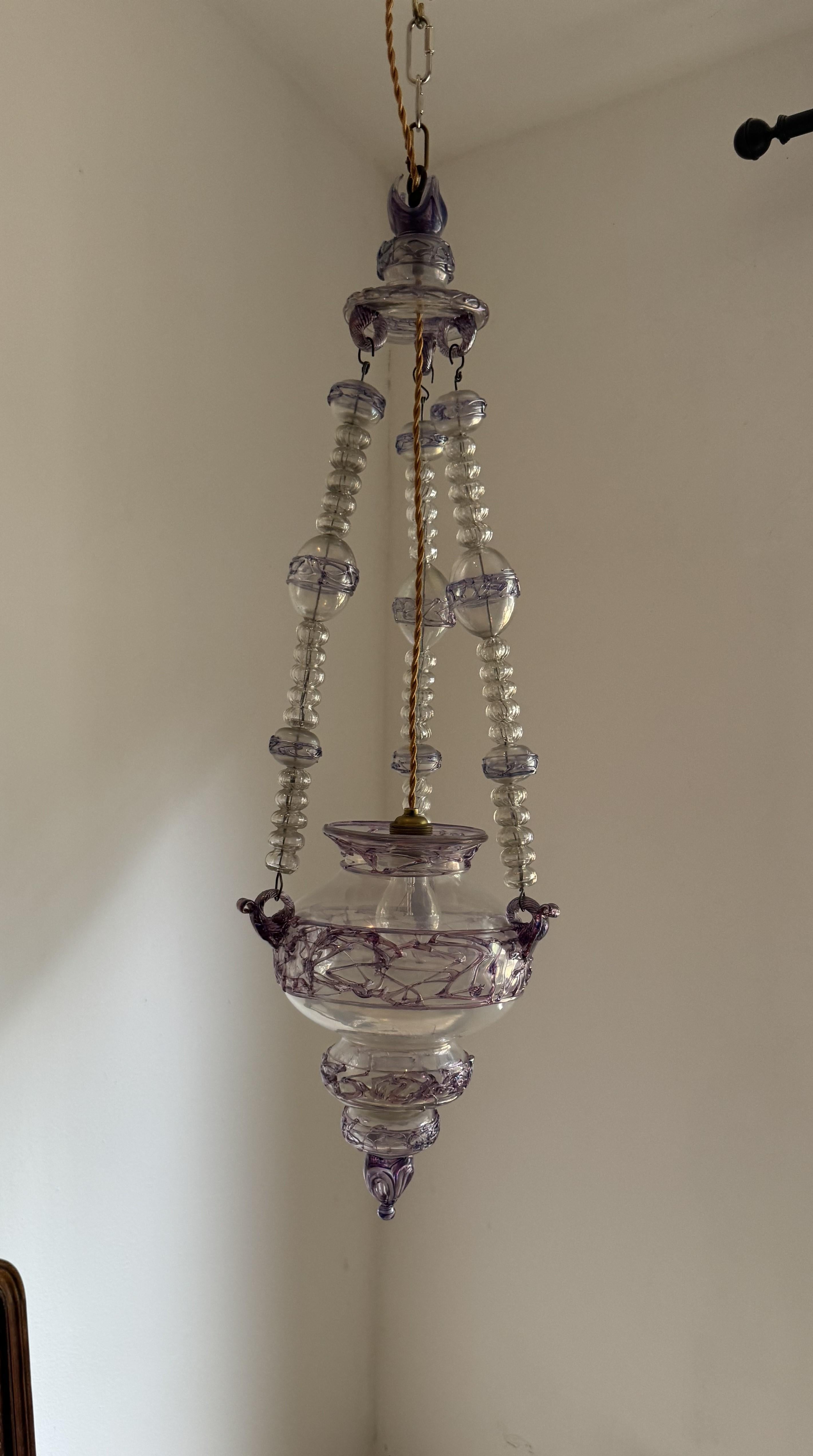 Magnifique lanterne italienne ancienne.
Insolite et unique survivant de son époque, cette lanterne montre deux influences très claires dans sa fabrication, d'abord la décoration des filaments de verre violet et bleu qui évoque les inscriptions sur