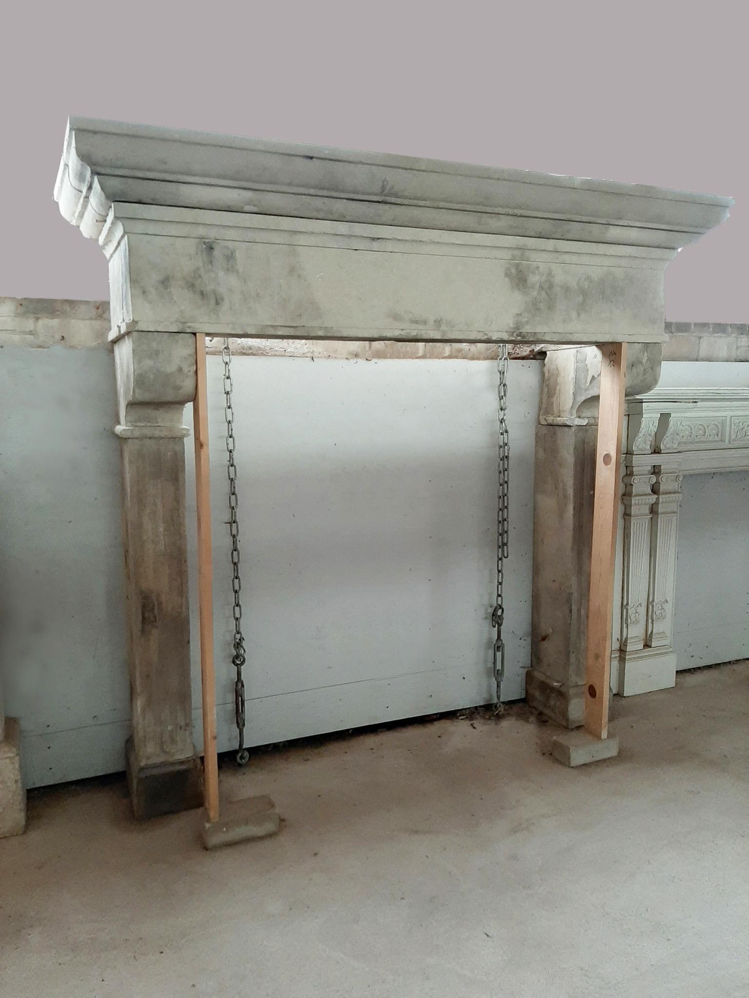 An Antique Italian Limestone Fireplace from the 19th century. With its substantial size, reminiscent of a castle hearth, and elegant fluted jambs, this fireplace is a striking addition to any space and brings a touch of historical charm to your