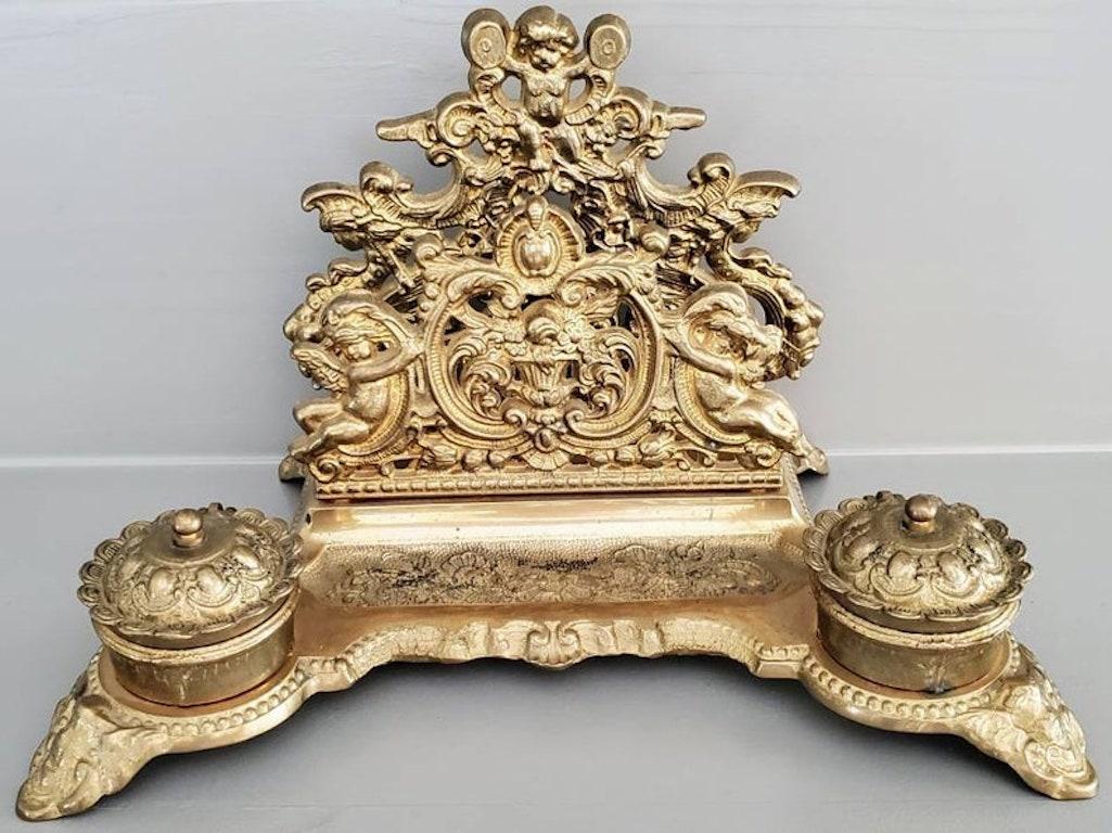 A late 19th century Italian gilded solid brass desk ornament. The elaborately decorated, highly detailed, Louis XV style, Rocaille form encrier, with a raised back single slot letter holder decorated with ornate scrollwork, floral, foliate and putti