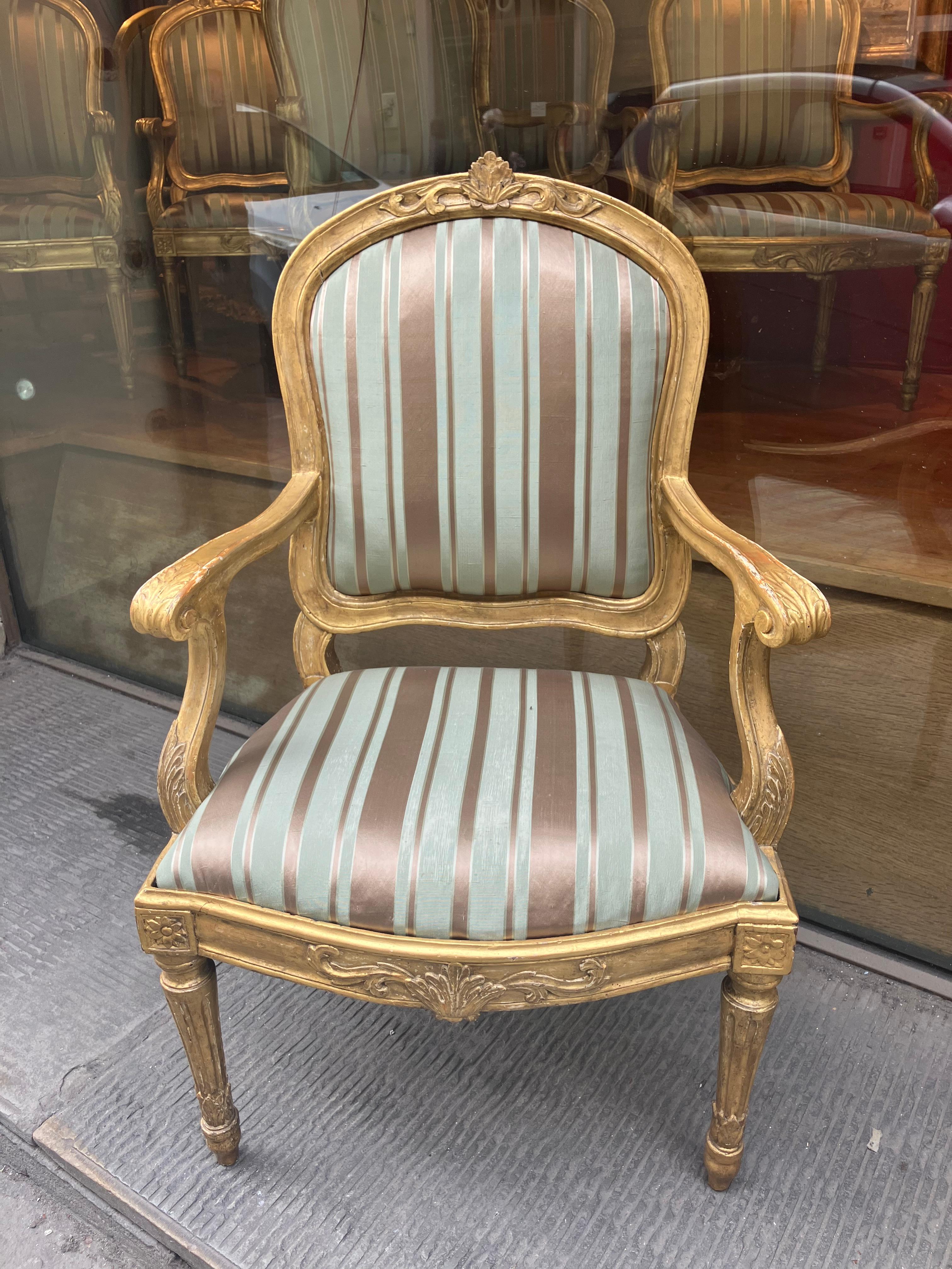 A fabulous set of six antique early 18th century Louis XVI  armchairs, masterfully hand carved and entirely gilded with gold leaf. The curved backrest centered by a sculpted pattern of leaves and scrolls, which are repeated on the apron and on the