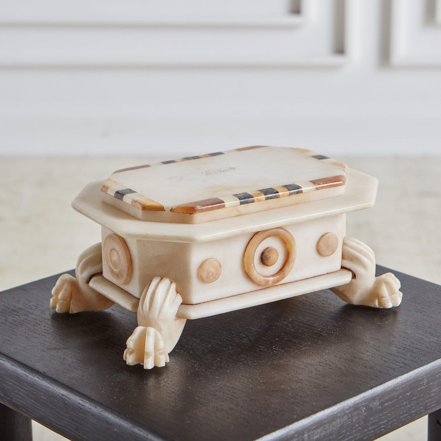 A gorgeous antique Italian box hand carved from a cream marble with textured claw feet and geometric details. This box has a lid with an inlaid marble trim in cognac and gray hues. Sourced in Italy.