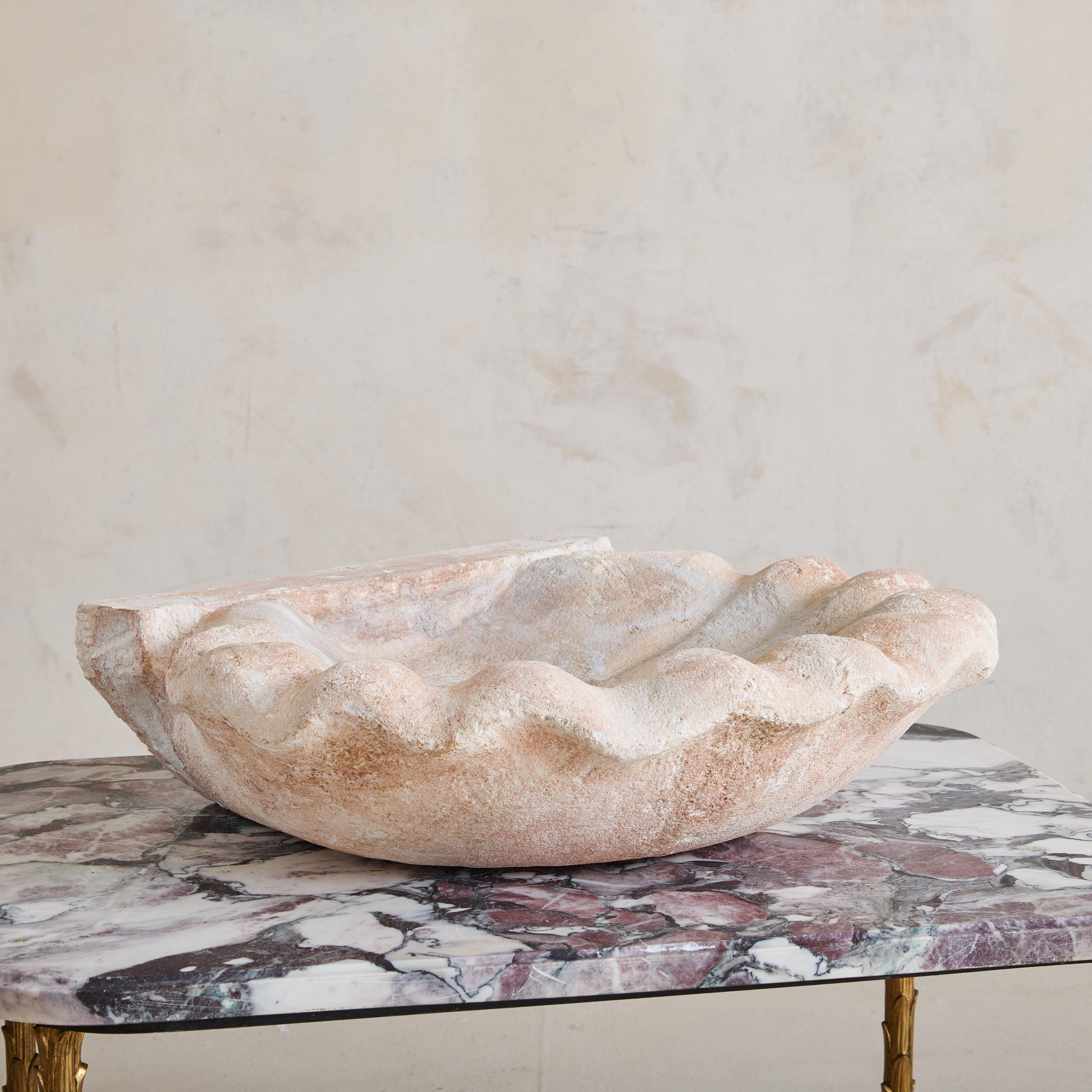 A mid-19th century marble sink, crafted in Italy well over one hundred years ago. Hand-carved from natural stone, this basin showcases the organic beauty of a scalloped shell. Its weathered patina and soft blush tones enhance its character, telling