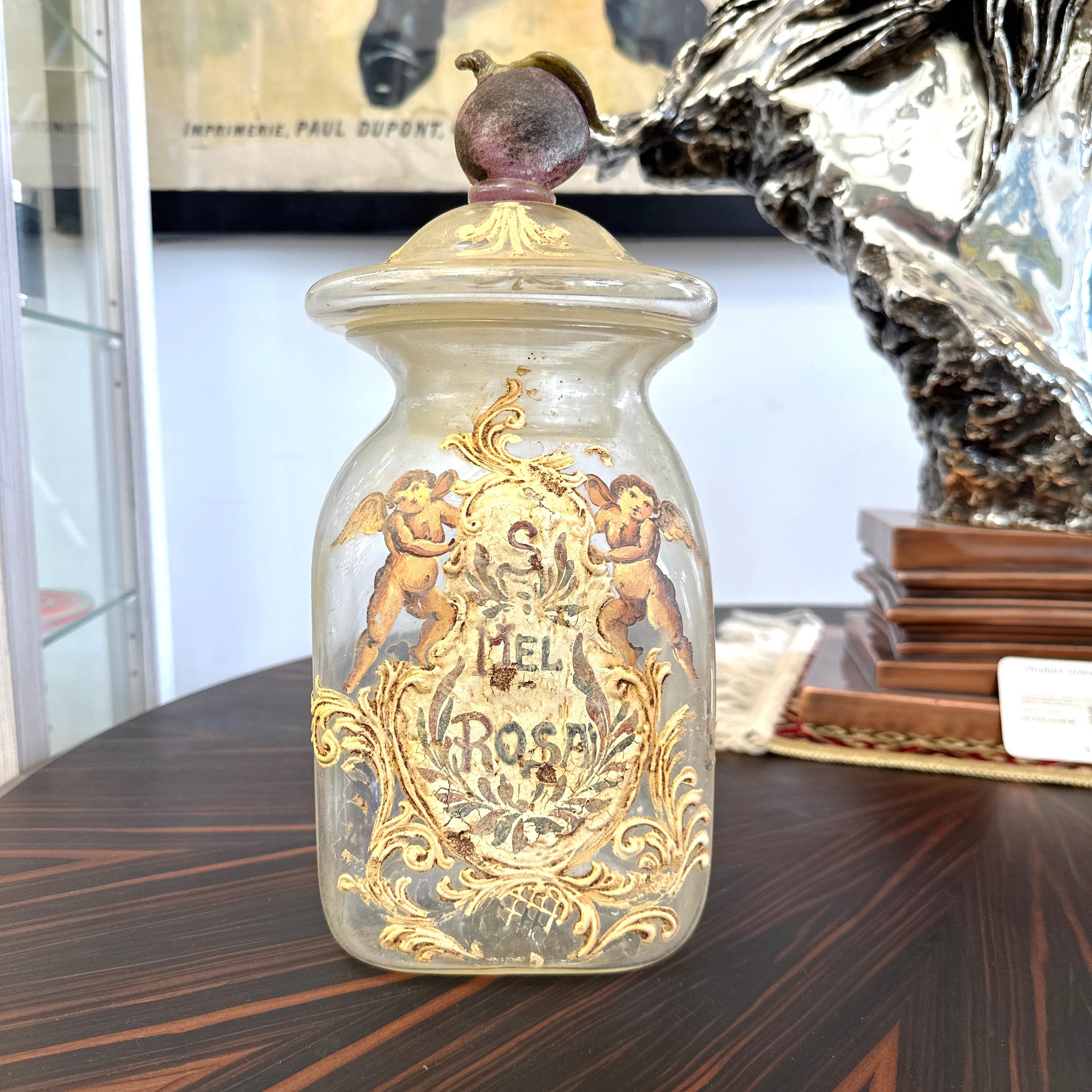 Here is a beautiful, rare and large Antique Italian Murano Glass Pharmacy Apothecary Jar. Elaborately hand painted and gilt on a clear Murano glass. Featuring an apple with leaf on the lid. Reads S. MEL ROSA in Latin which translates to Honey Rose.