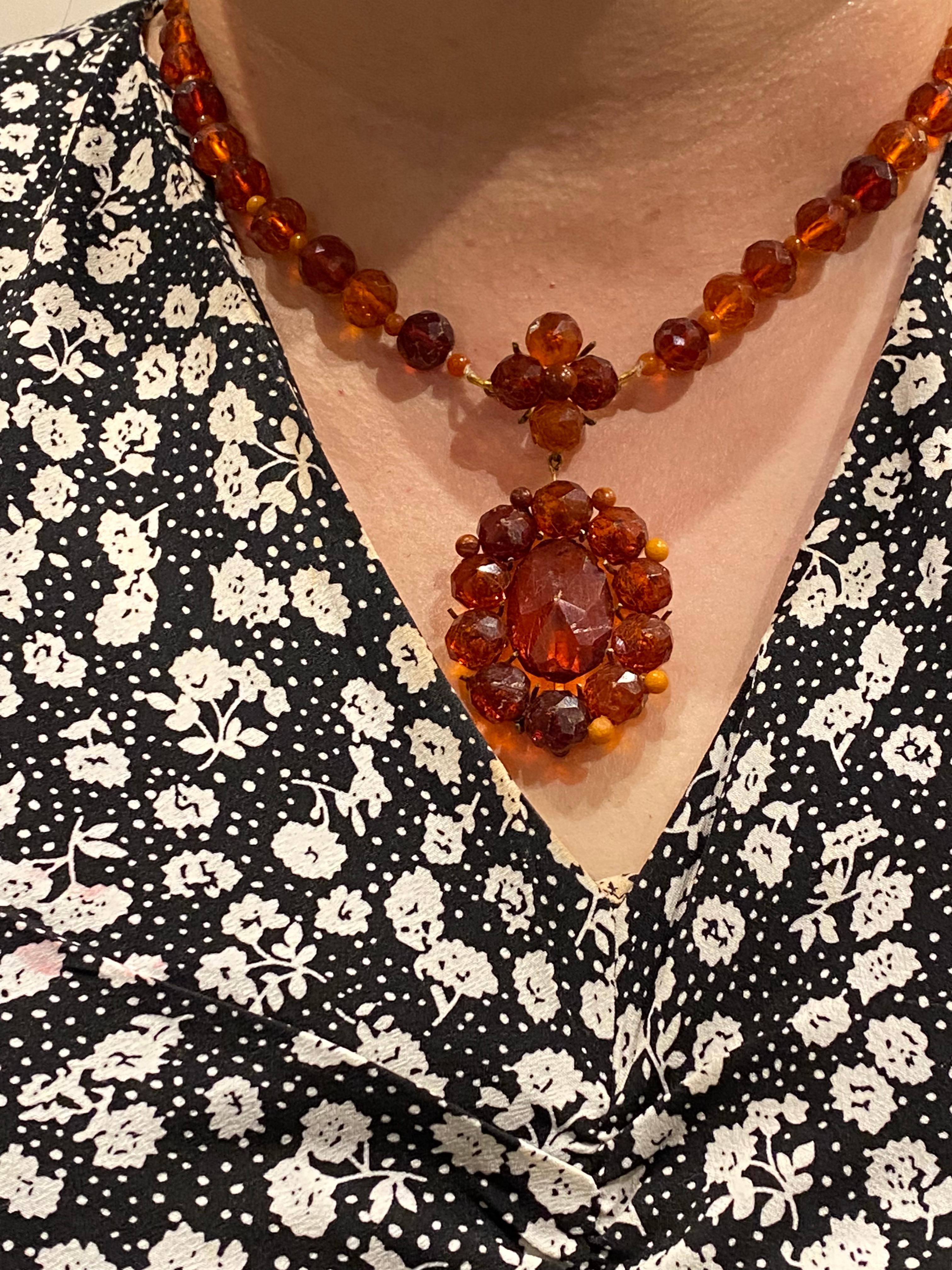 This antique piece from Southern Italy features: 

 

Oval shaped Natural Amber cluster pendant, 

measuring 35 x 45mm, 

surmounted by a 5-bead flower-shaped cluster, 

8 - 9.5mm faceted and smooth bead in the centre  

 

Joint to a necklace,