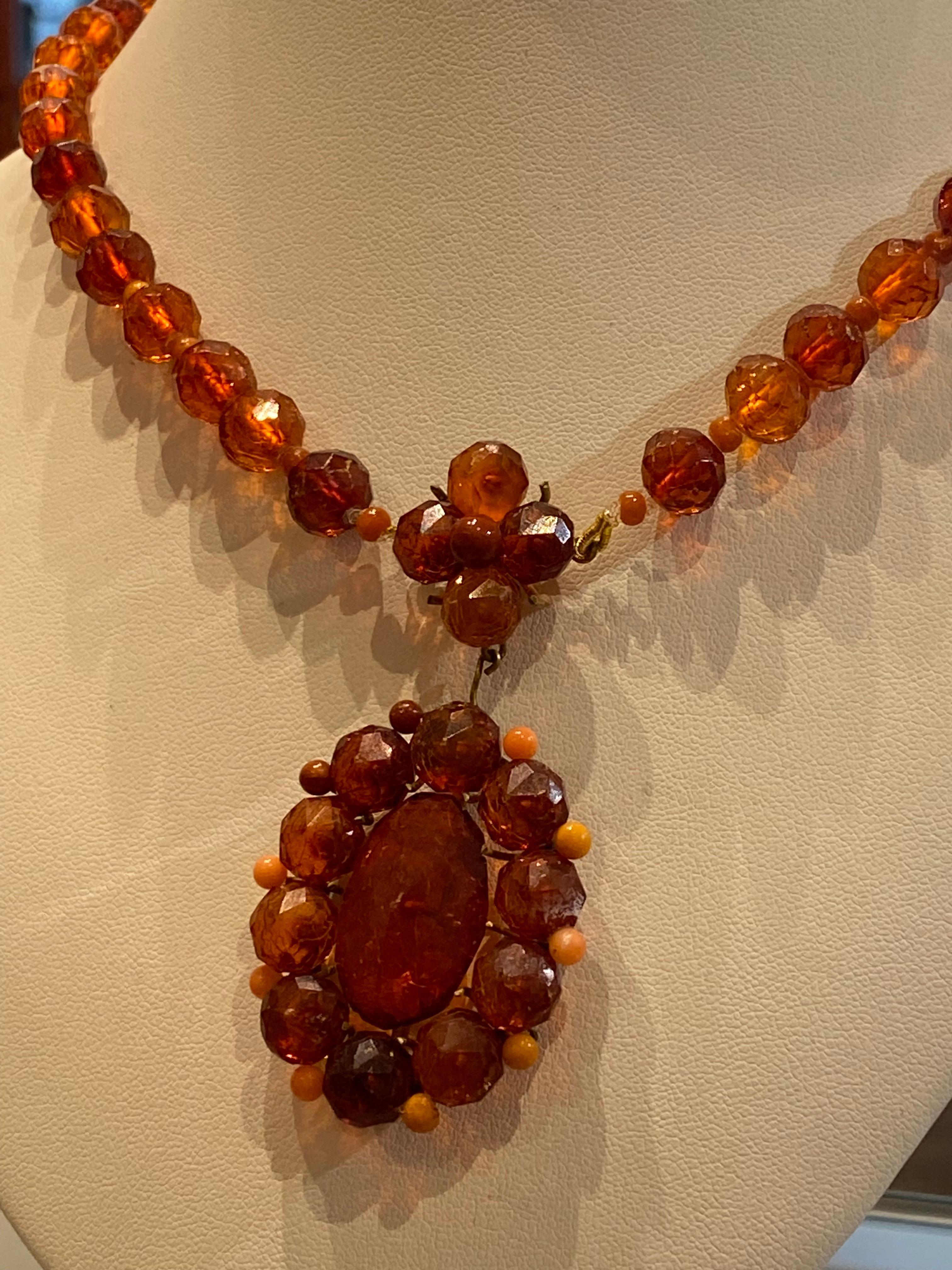 Cette pièce antique du sud de l'Italie présente les caractéristiques suivantes : 

 

Pendentif de forme ovale en forme de grappe en ambre naturel, 

mesurant 35 x 45 mm, 

surmonté d'une grappe de 5 perles en forme de fleur, 

8 - 9,5 mm de perle