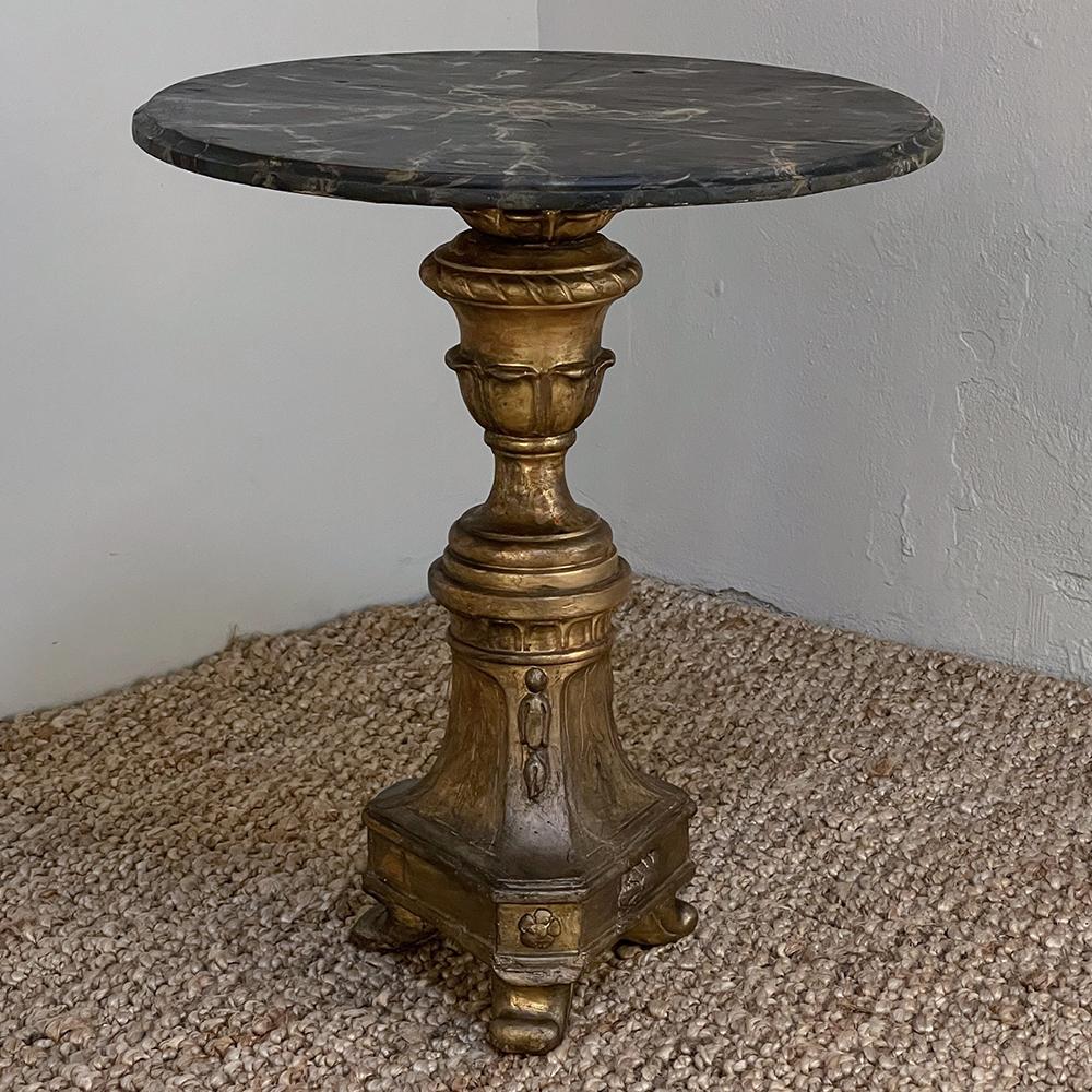 L'antico tavolo da lampada neoclassico italiano in finto marmo dorato è un piccolo gioiello caratterizzato da un piano dipinto in finto marmo e da un piedistallo dorato intagliato a mano dal design classico con base a treppiede che lo rende un
