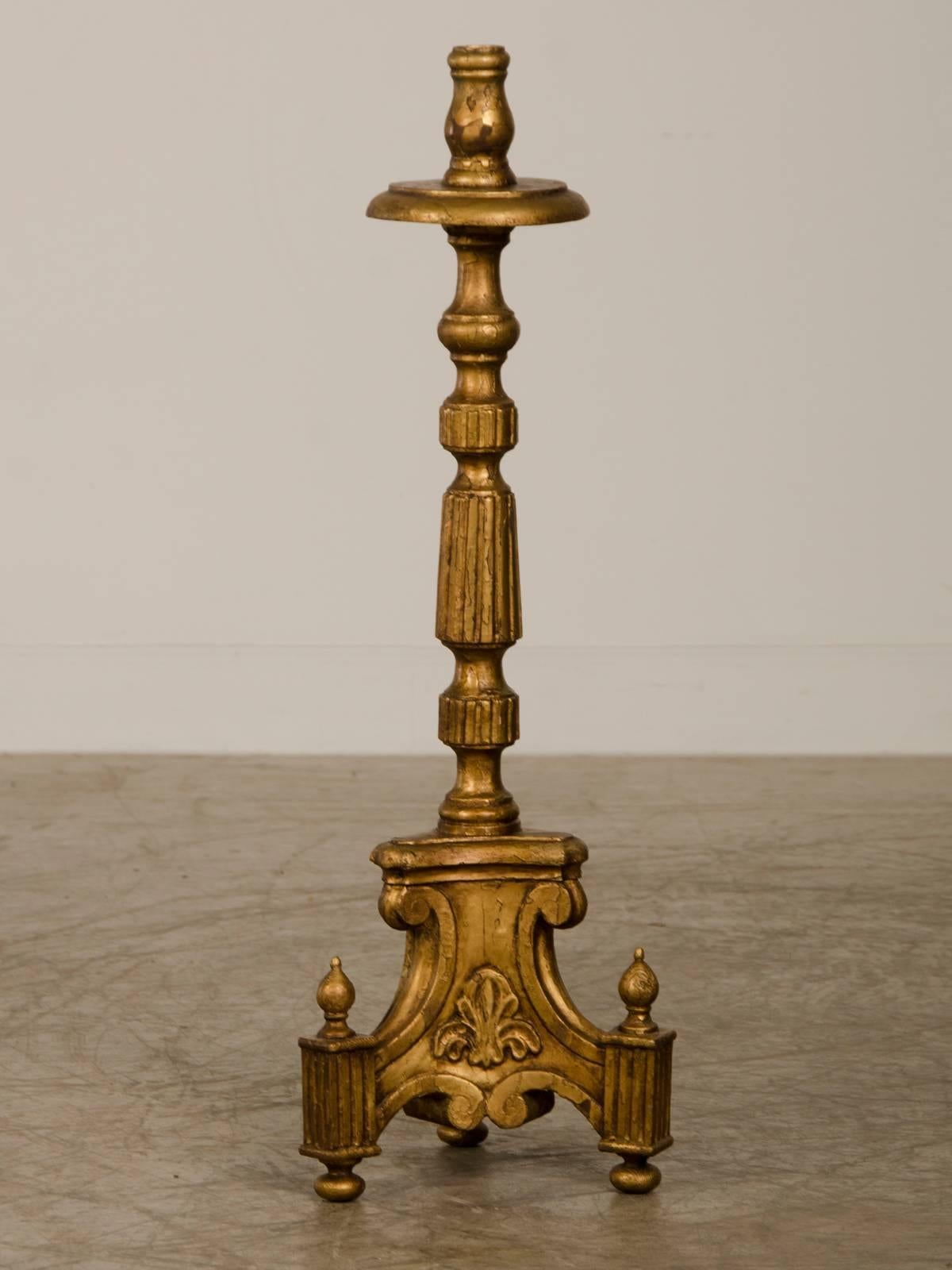 A handsome antique Italian neoclassical style gold leafed candlestick from Italy circa 1885. This elegant candle stick derives its visual appeal from the balance and symmetry of its constituent parts. The base of the candle stick has three sections