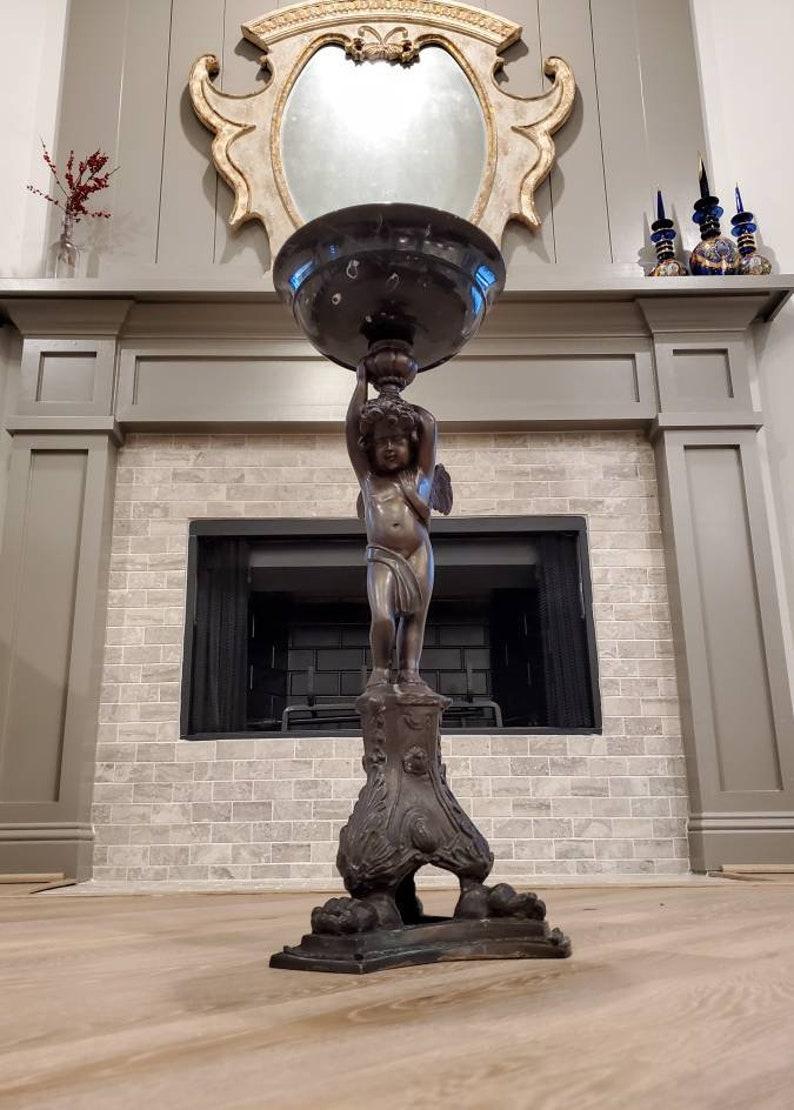 Eine stilvolle und hochwertige Bronzeskulptur im neoklassizistischen Stil in Form einer raffiniert stehenden geflügelten Putte (Cherub-Engel), die ein Marmorbecken hält, aus dem frühen 20. Jahrhundert. 

Diese auffällige Bronze zeigt eine fein