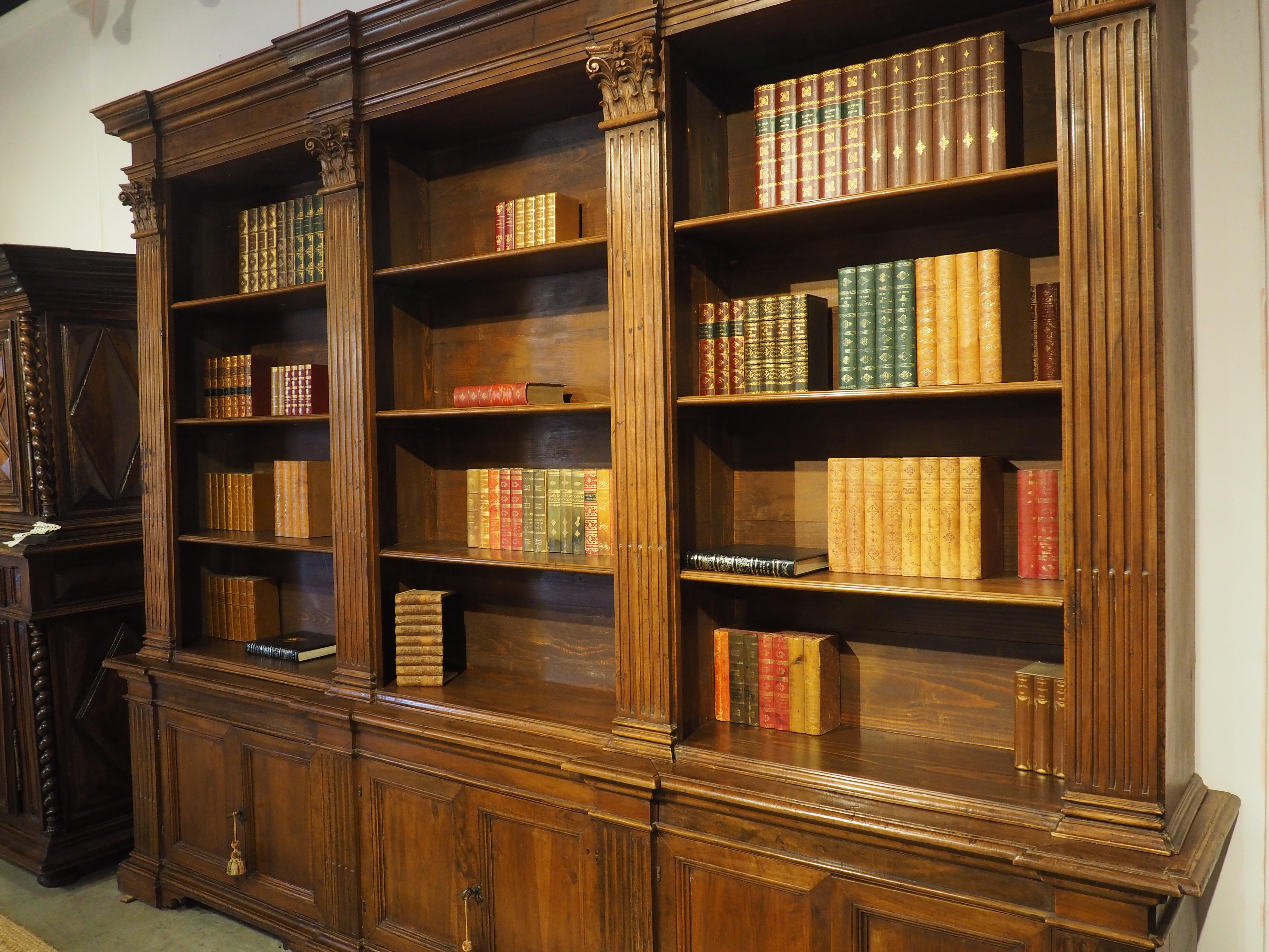 Esta impresionante librería italiana triple presenta un cuerpo superior abierto sobre una sección inferior de tres puertas dobles. Algunos elementos de madera de nogal tallada a mano datan del siglo XVIII (sobre todo las pilastras, los capiteles y