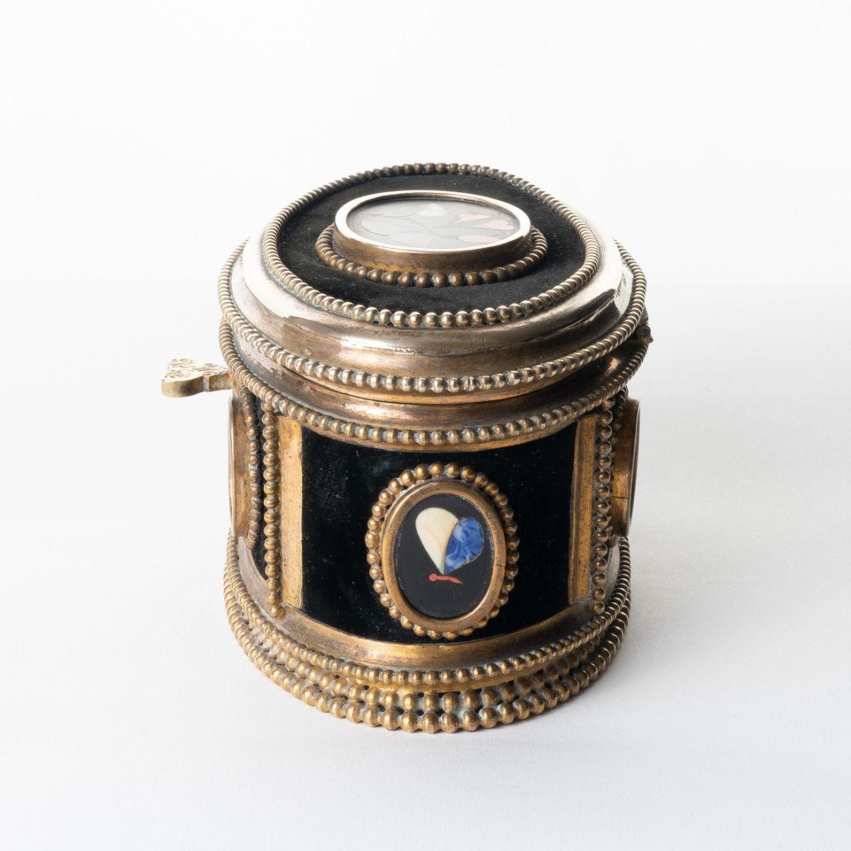 Italian jewelry cask in cast bronze with a beaded edge, oval framed, and set with pietra dura (cut & fitted) ovals of flowers & butterflies in oval beaded frames backed with black silk velvet. The hinged lid is keyed and opens to a blue silk velvet