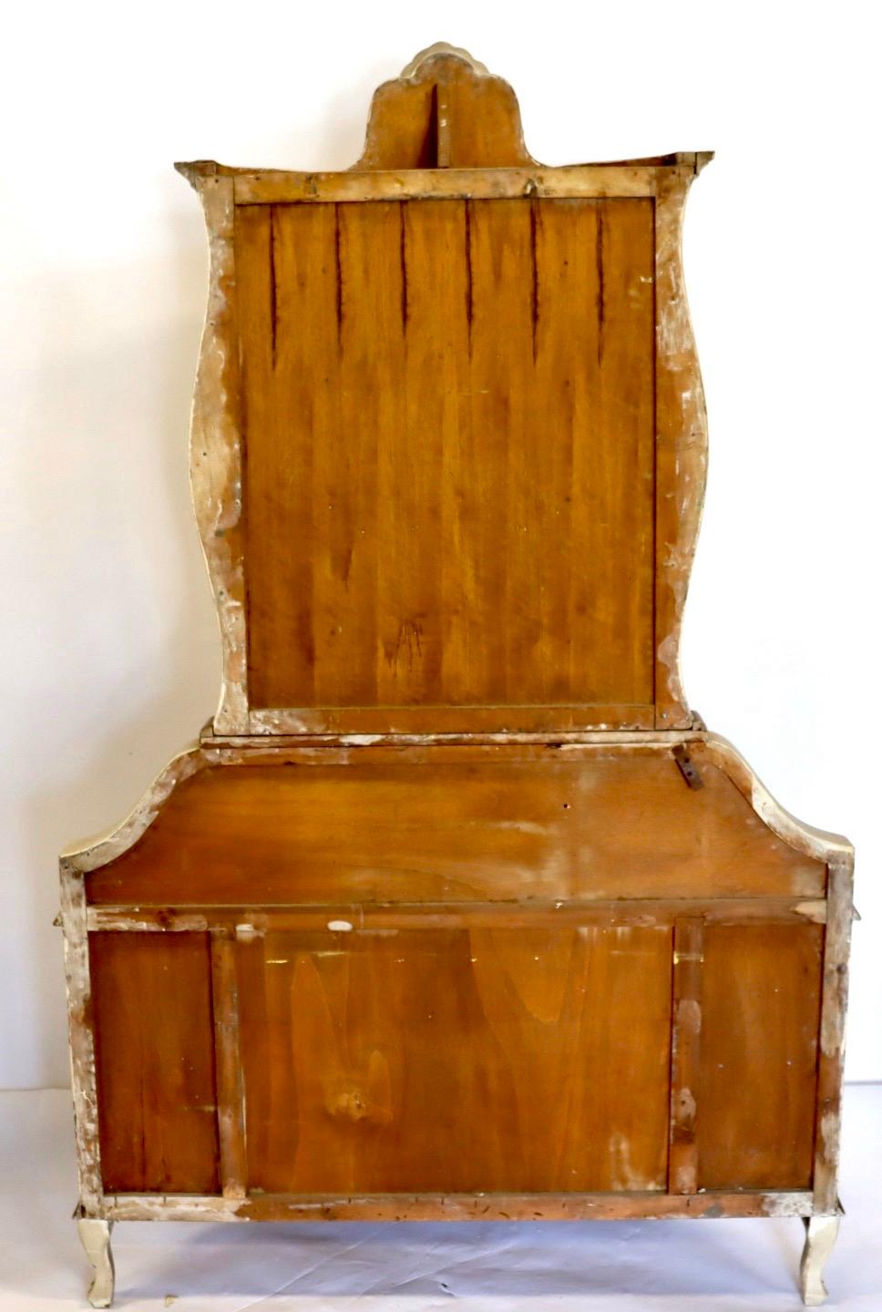 An Italian paint decorated secretary desk in antique white and orange with gold gilt detail. It features a unique shape with bookcase top over a drop front with an interior desk. The lower section has three drawers. Finely painted with flowers and