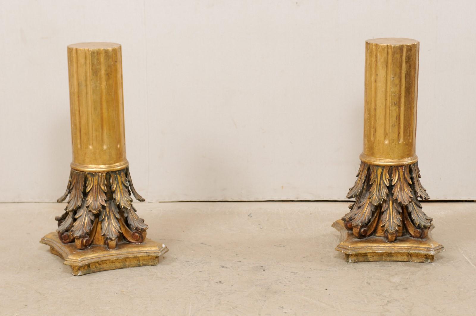An Italian pair of carved and giltwood three feet tall pedestals from the early 20th century. This antique pair of architectural pedestal columns from Italy, standing approximately three feet in height, are gesso and gilt over wood. The round-shaped
