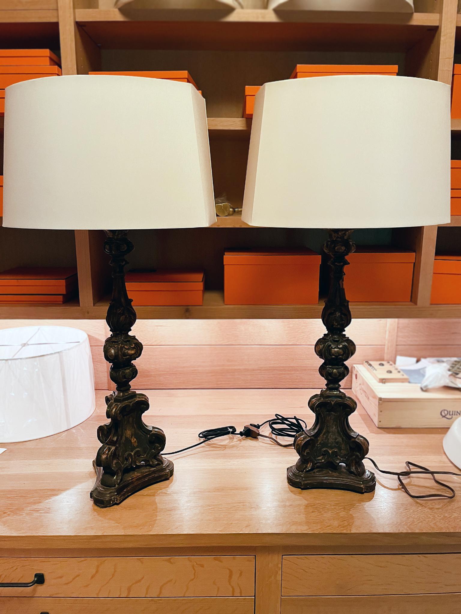 Estas lámparas de sobremesa altas están fabricadas con cuerpos de madera italiana de principios del siglo XX con detalles ornamentalmente tallados y restos de su acabado policromado original. Las lámparas se han recableado con casquillos dobles y se