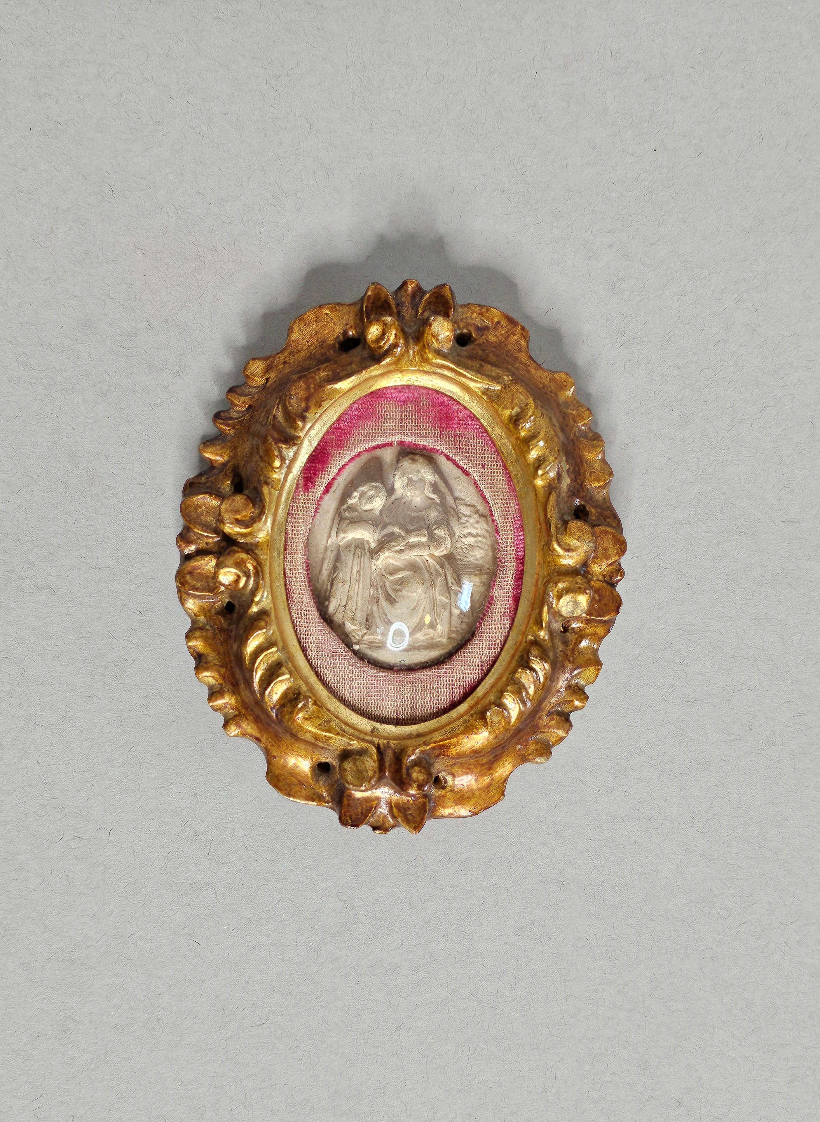 Raro relicario antiguo italiano enmarcado en madera dorada. Siglo XVIII/XIX, marco de madera dorada tallada a mano que alberga una excepcional talla en relieve, que representa a Santa Ana enseñando a la Virgen, escultura que se cree tallada en