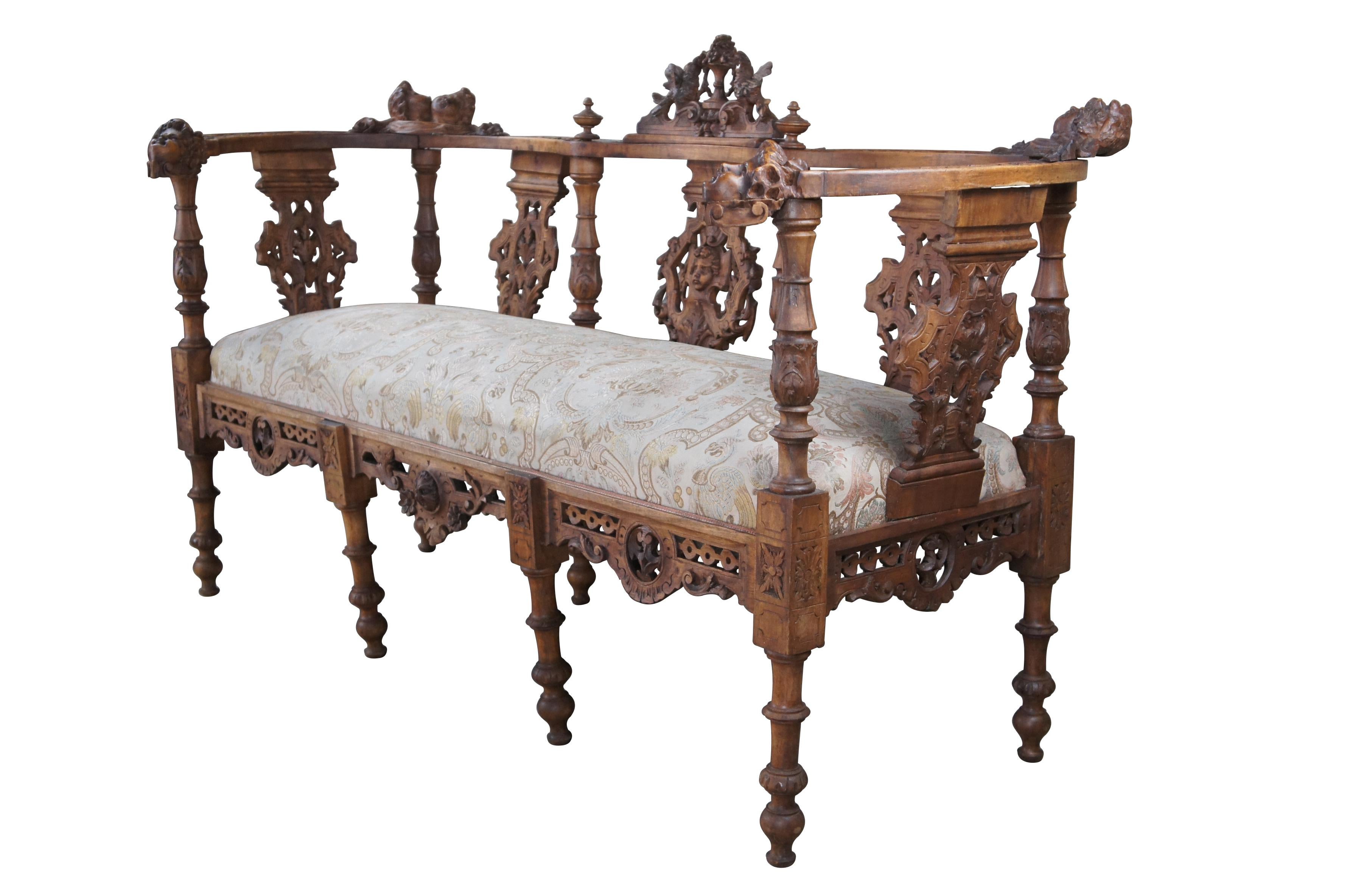 Antique Italian Neo-Renaissance parlor settee / loveseat / bench, circa 1870s.  Made of walnut featuring Neoclassical styling with high relief figural carvings of cherubs / puttis, Northwind faces, doves / birds, acanthus / floral and reticulated /