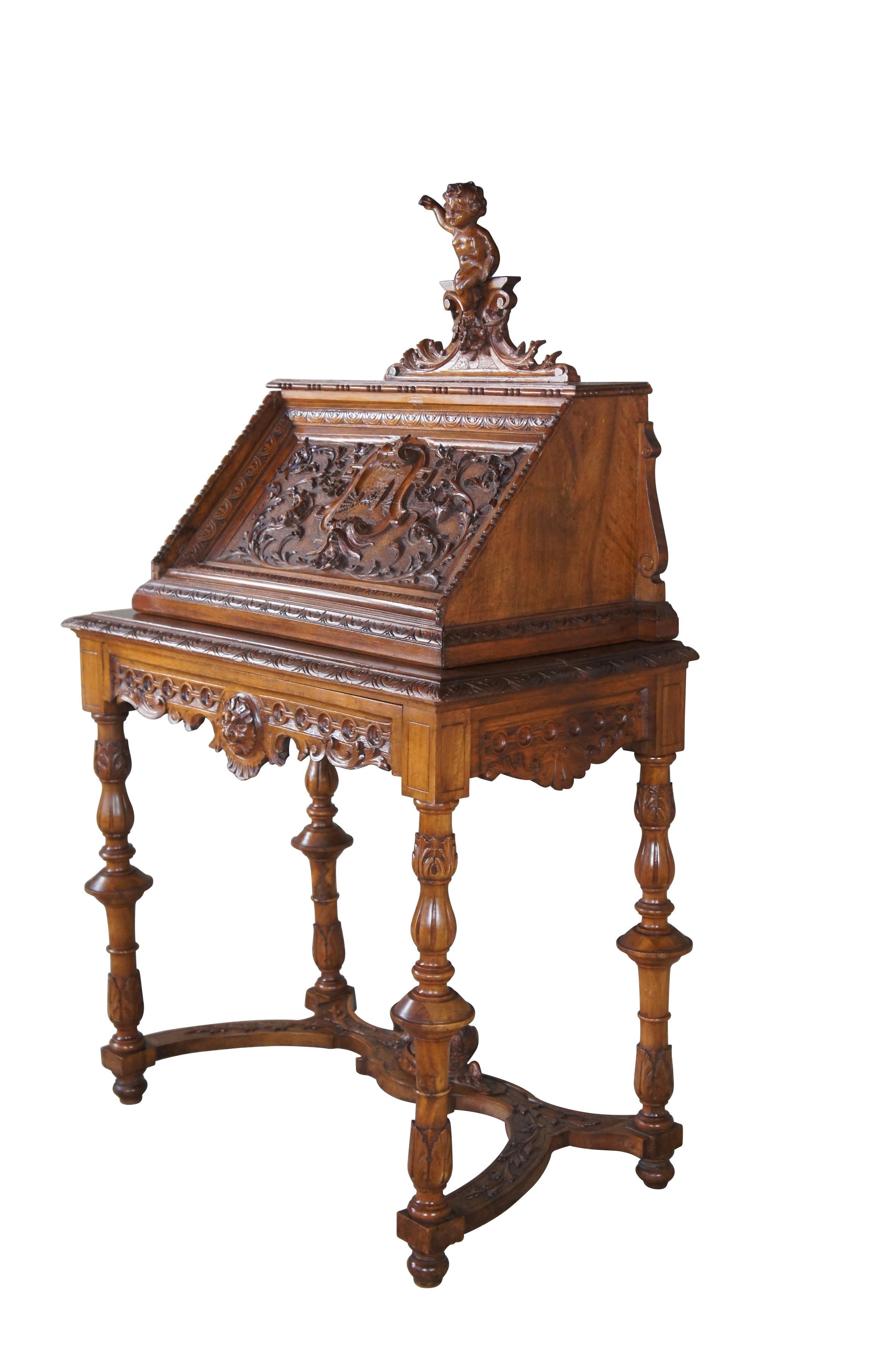 Antique Neo-Renaissance Revival writing desk.  Made of walnut featuring Neoclassical styling with high relief figural carvings of cherubs / puttis, Northwind faces, and acanthus / floral designs.  The desk features a drop front door with griffons