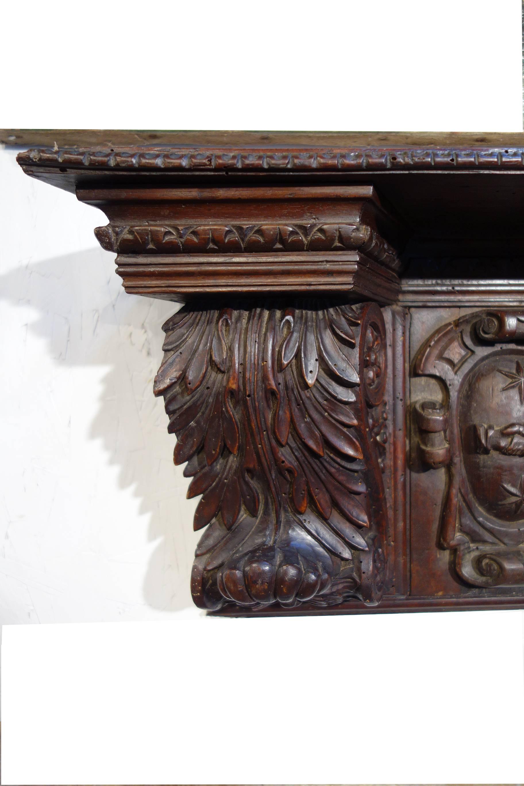 Striking mid-19th century old Italian walnut architectural element, deeply hand-carved Renaissance features, coat of arms, tapered width with functional shelf top.

Measures: 34