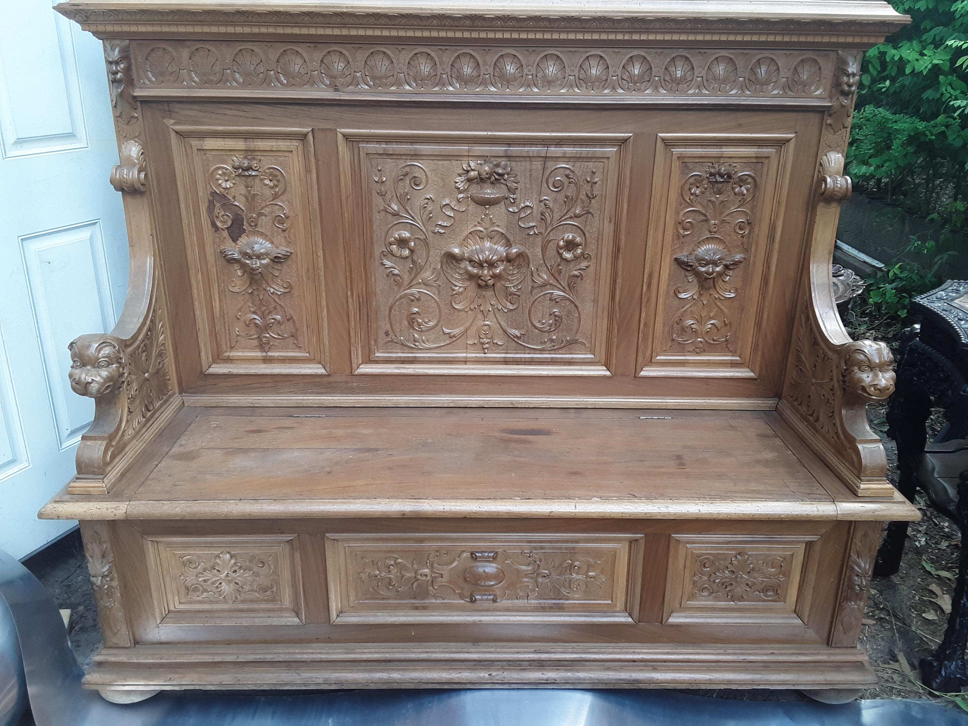 Antique Italian Renaissance style bench in heavy carved walnut, Ca 1860 Impressive 19th Century bench of solid walnut with heavily hand-carved Renaissance motif of dragons, lion heads, chalise & vines. The seat lid opens to reveal storage.