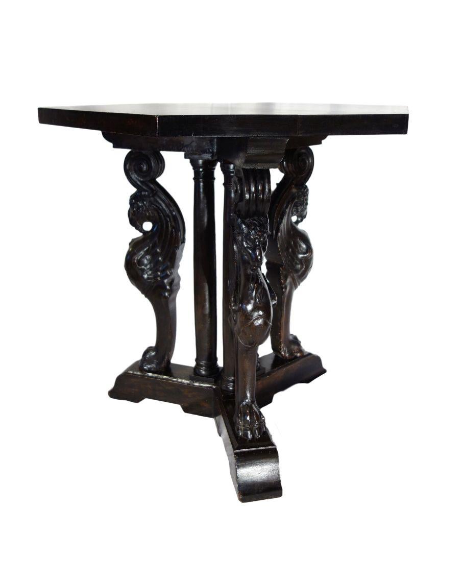 Striking Renaissance Revival period figural carved triple pedestal occasional table featuring Griffons - the legendary mythological hybrid of Eagle & Lion. Relative to the Egyptian Sphinx, the Griffon has been depicted in Europe in Roman bronzes of