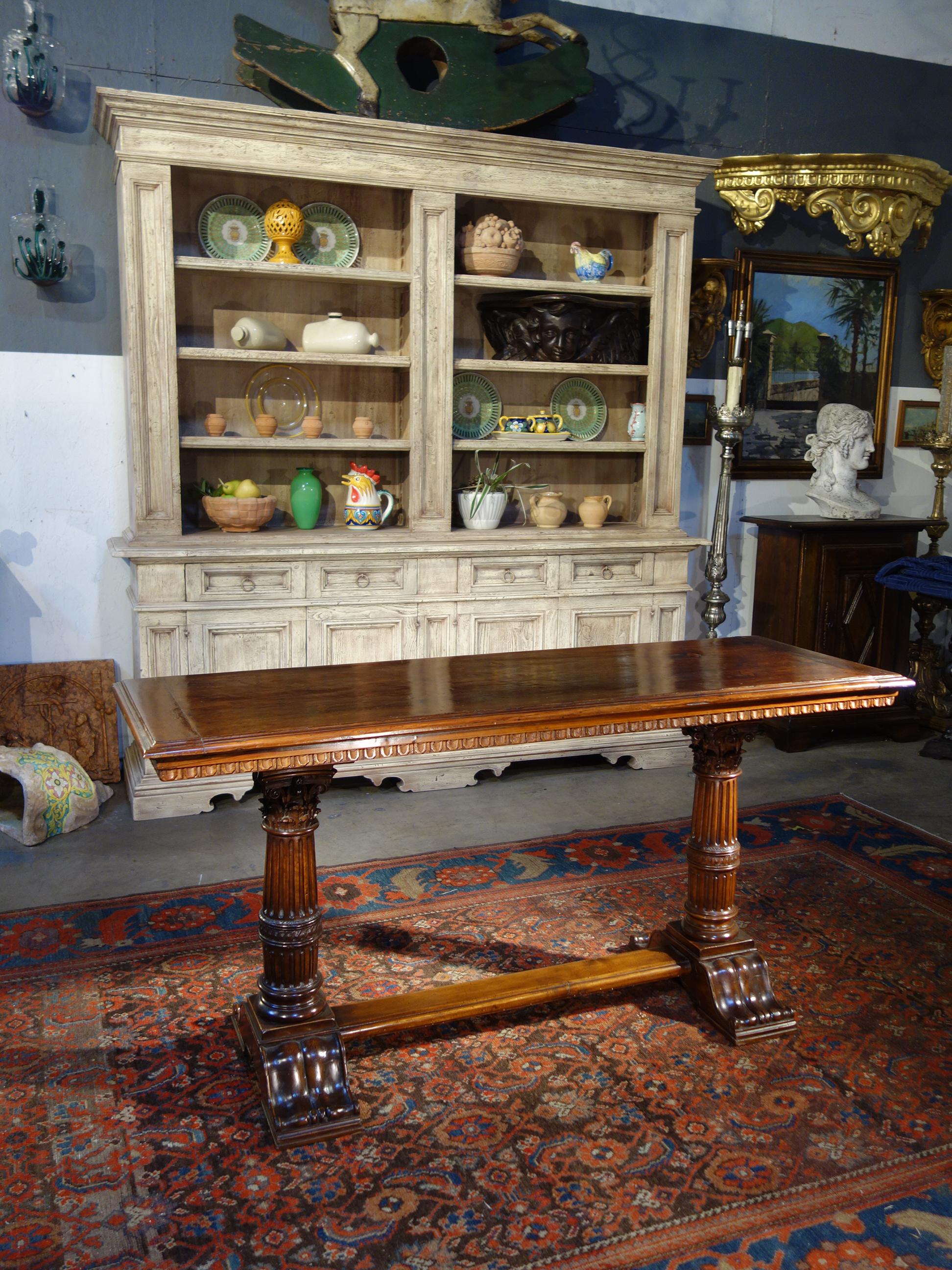 Exceptional Renaissance style hand carved detail is exhibited in this solid Italian walnut console, with dentil decoration under the slab top with end frames. Elegant Corinthian column pedestals artfully create the trestle base. Rich traditional