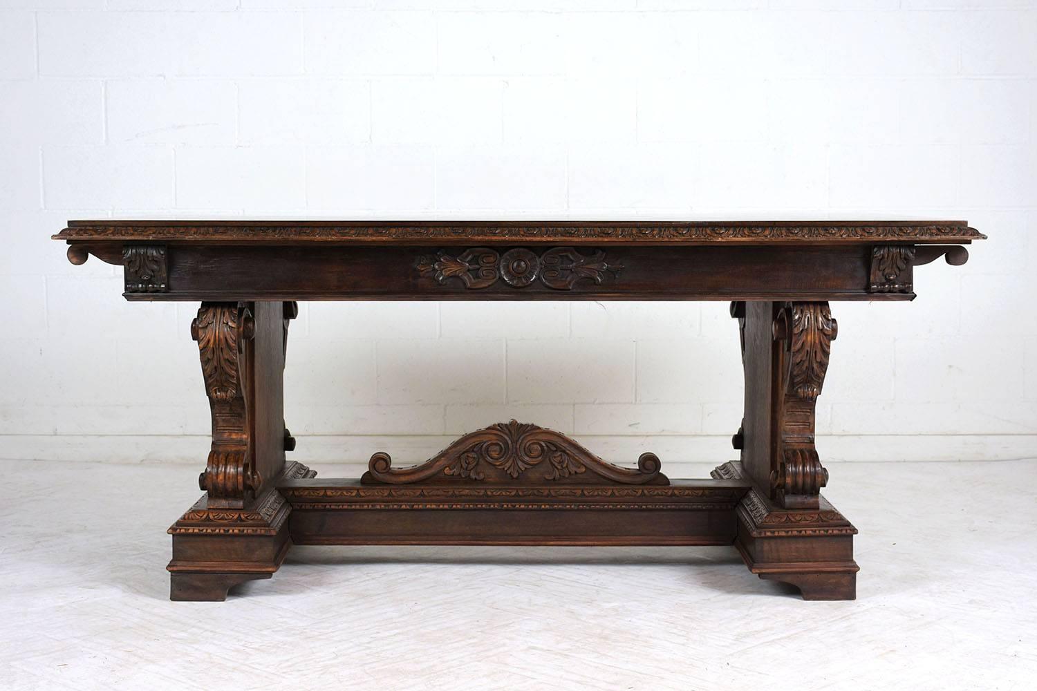 This heavily carved Italian Renaissance-style trestle dining table dates to the early 1900s. The table is made of walnut wood stained a rich walnut color with a polished finish. The table is adorned with carved details of acanthus leaves, scrolls,