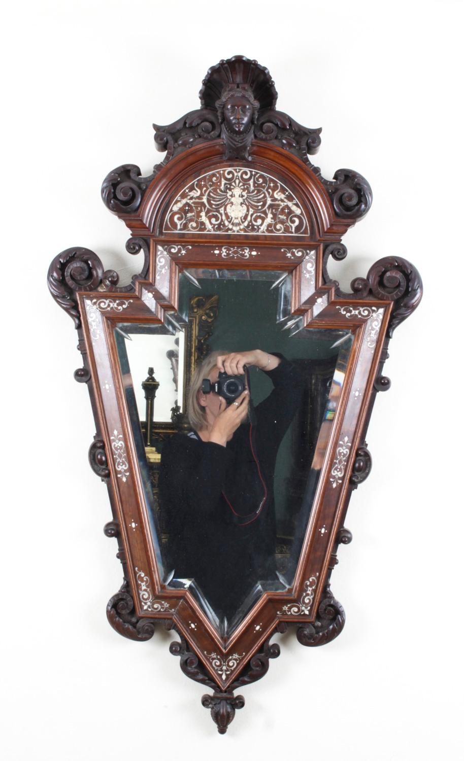 This is a beautiful antique Italian Renaissancce Revival carved walnut and bone inlaid wall mirror, dating from the late 19th century.

The mirror is set in a beautiful carved walnut frame surmounted with a portrait female mask, with 'C'
