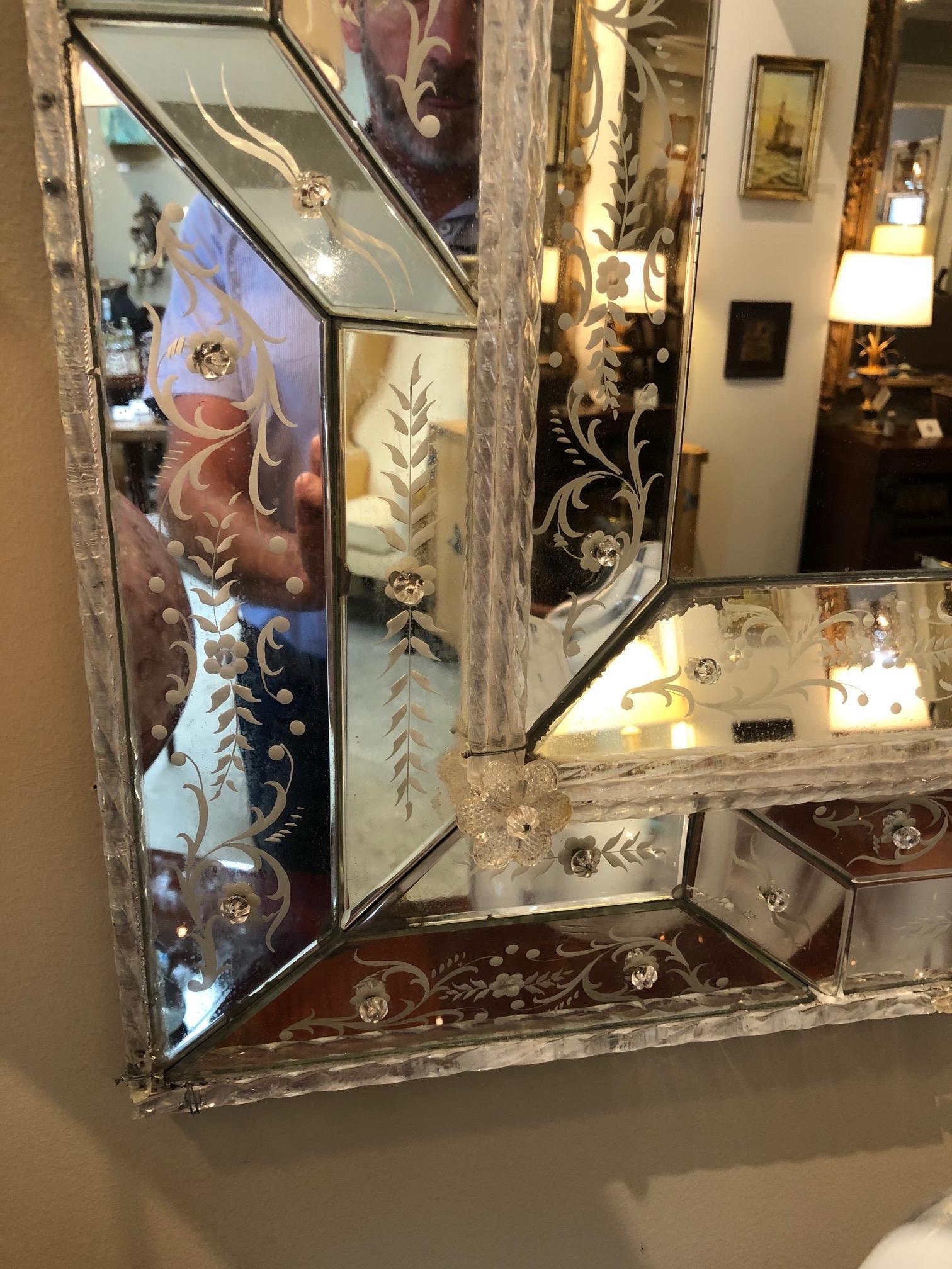 The central mirror plate within an outer frame of geometric reverse-etched mirrored elements secured with glass floral-form posts.