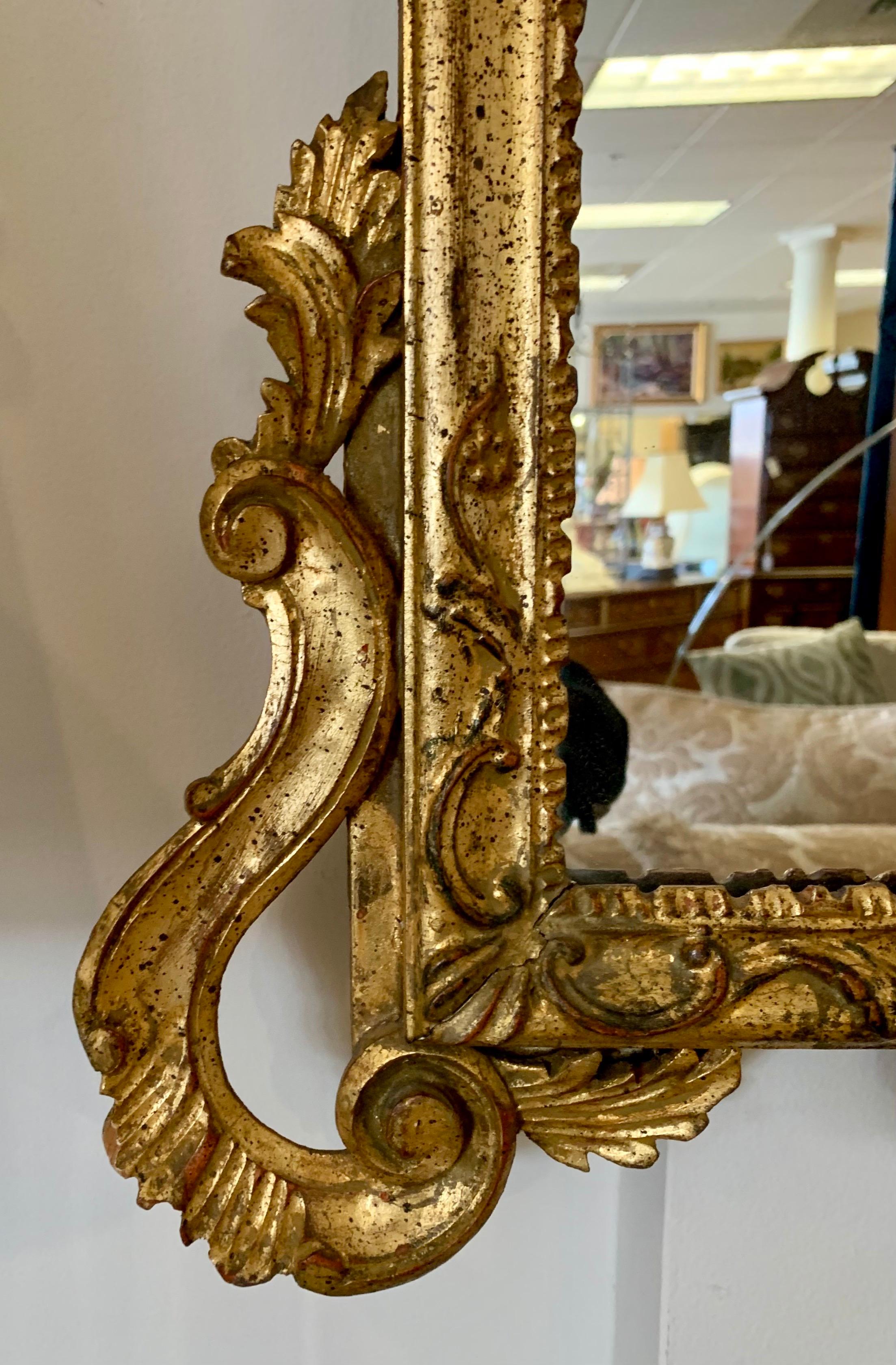 Carved and gilded shield shaped Rococo style Italian mirror with scrolls and acanthus leaf detail.