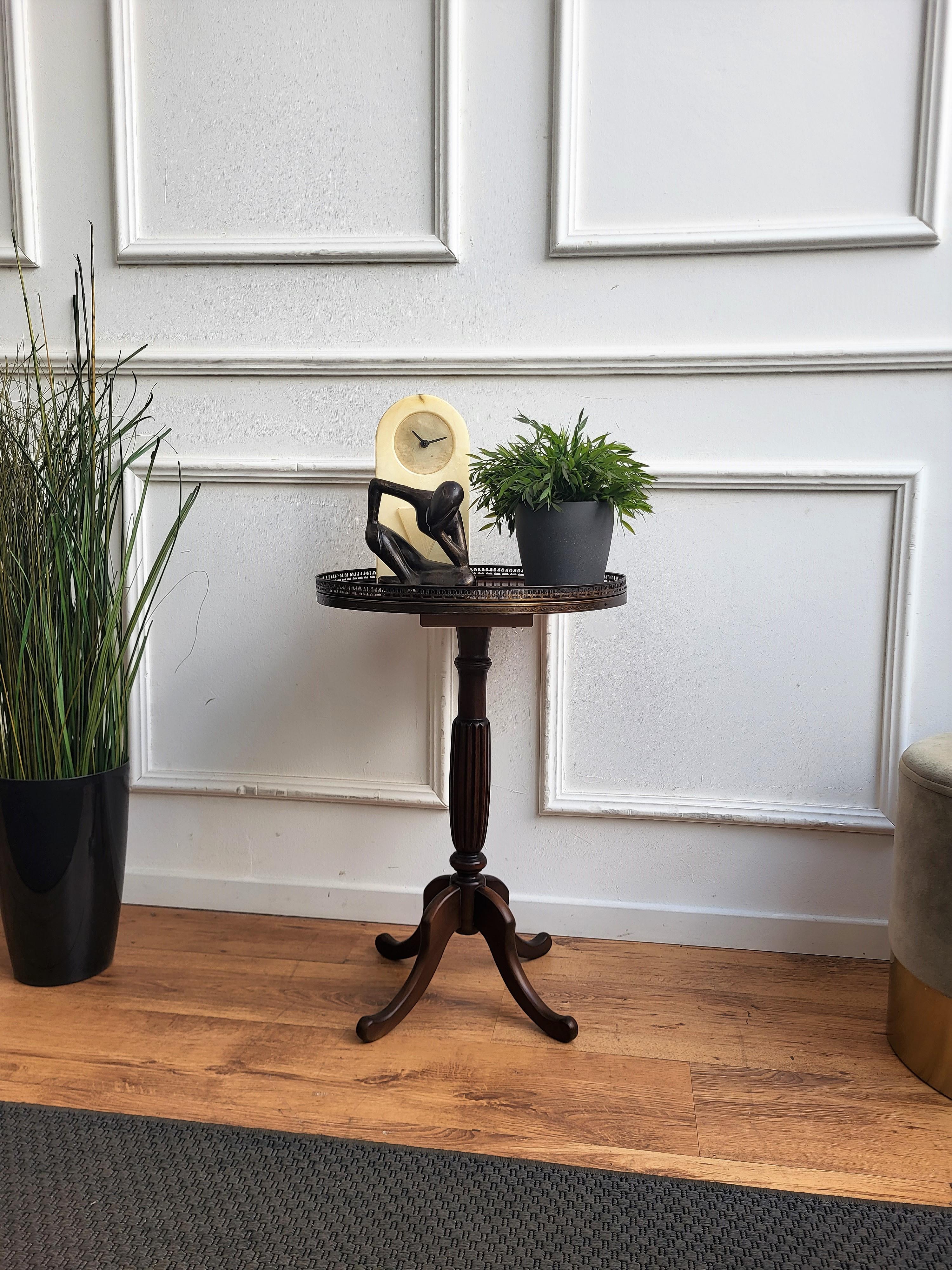 Beautiful antique Italian solid walnut side table features a round top with brass frame over a central beautifully crafted decor and four tripod legs. This Italian walnut side or coffee table with the rich and beautiful patina would look wonderful