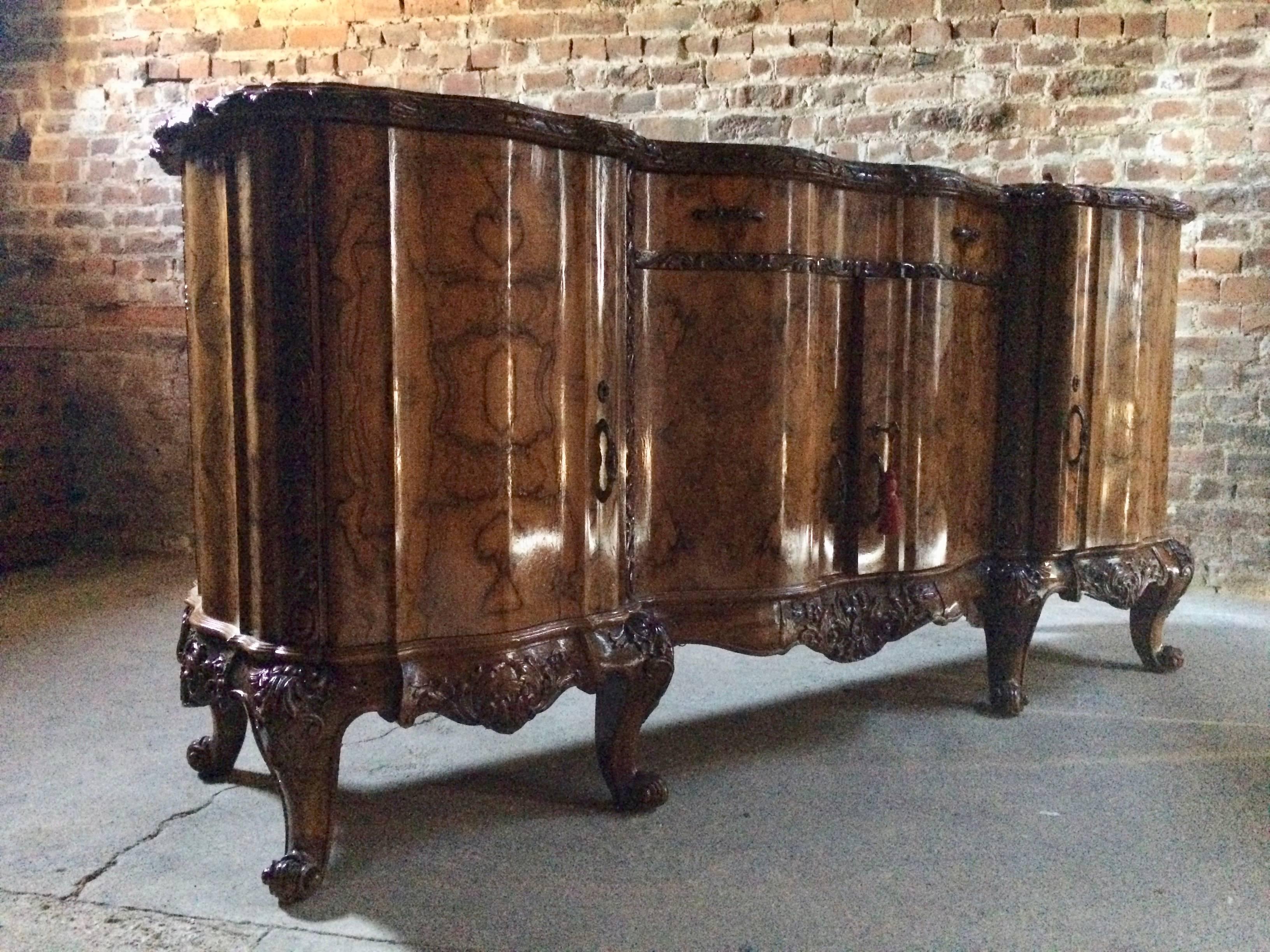 A beautiful 20th century antique style Italian Burr walnut marble topped sideboard credenza, the large black inlaid marble top with moulded top and serpentine front over two frieze drawers, over four serpentine fronted cupboards all with shelves