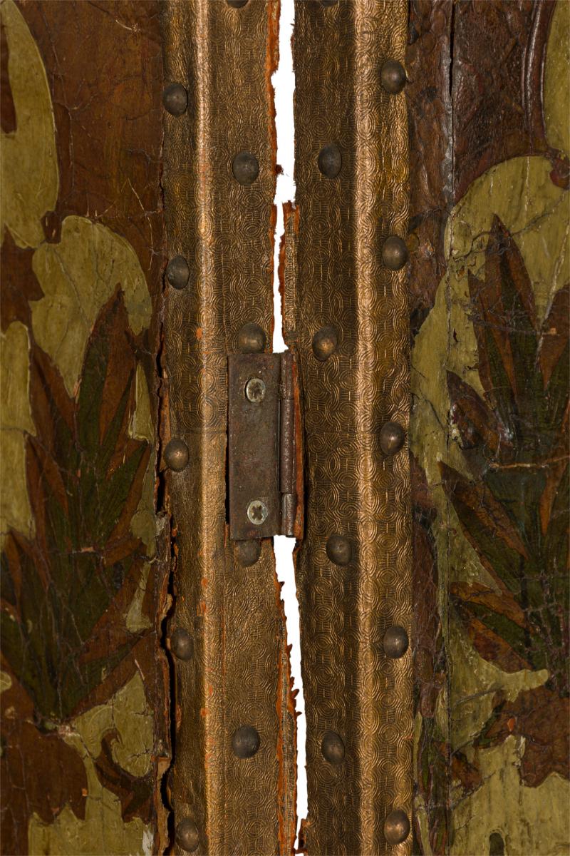 Italian (19th Century) four panel folding screen with brown and beige tooled leather panels featuring detailed floral designs, with brass nailhead trim and a black canvas-faced reverse.

Cracking and losses to leather panels.