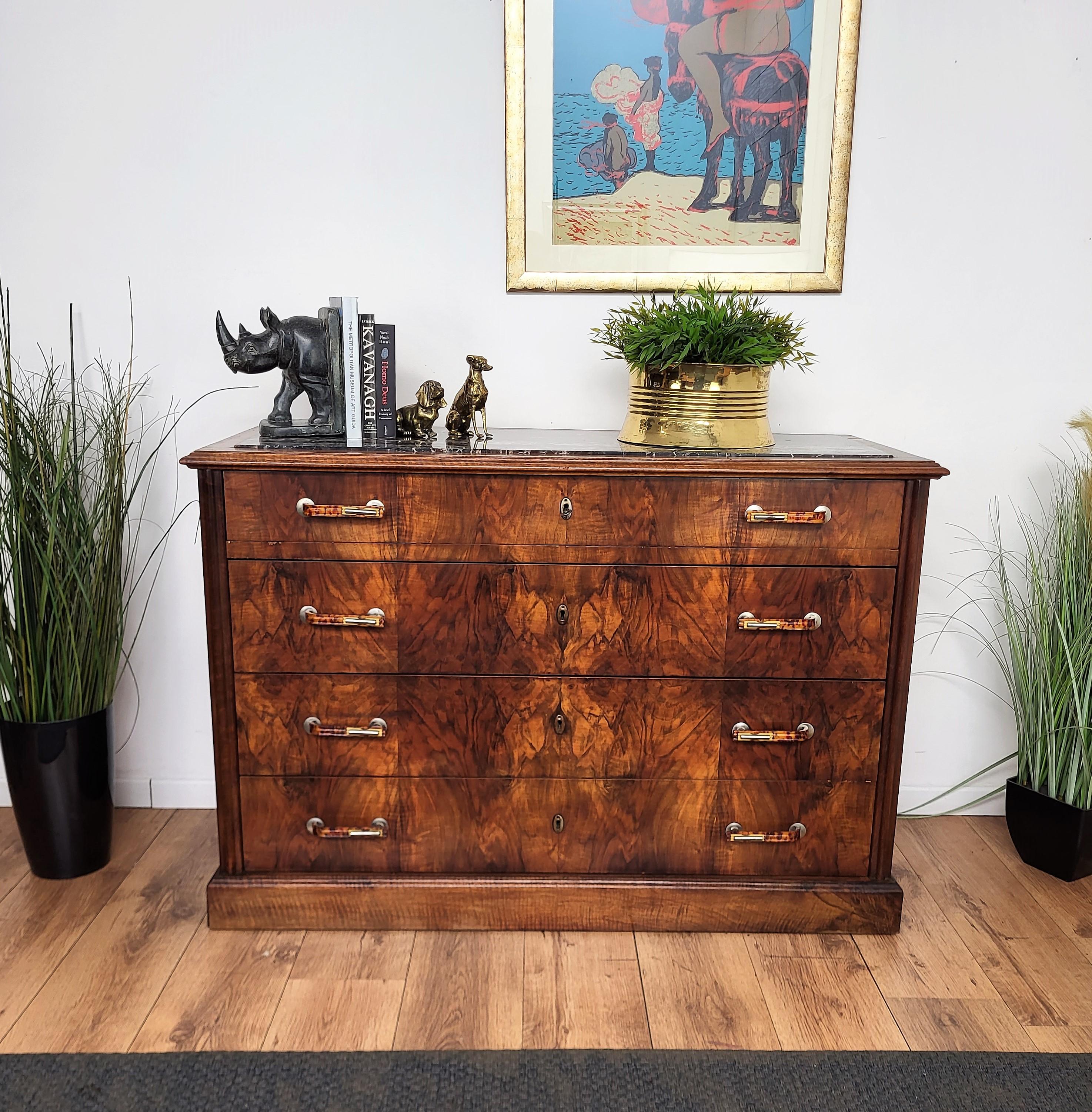 Very elegant Italian Art Deco Mid-Century Modern chest of drawers, commode cabinet, in beautiful veneer walnut wood, 4 drawers, and decorated handles with black Portoro marble top. Portoro is a high-quality black marble, where the vast crystalline