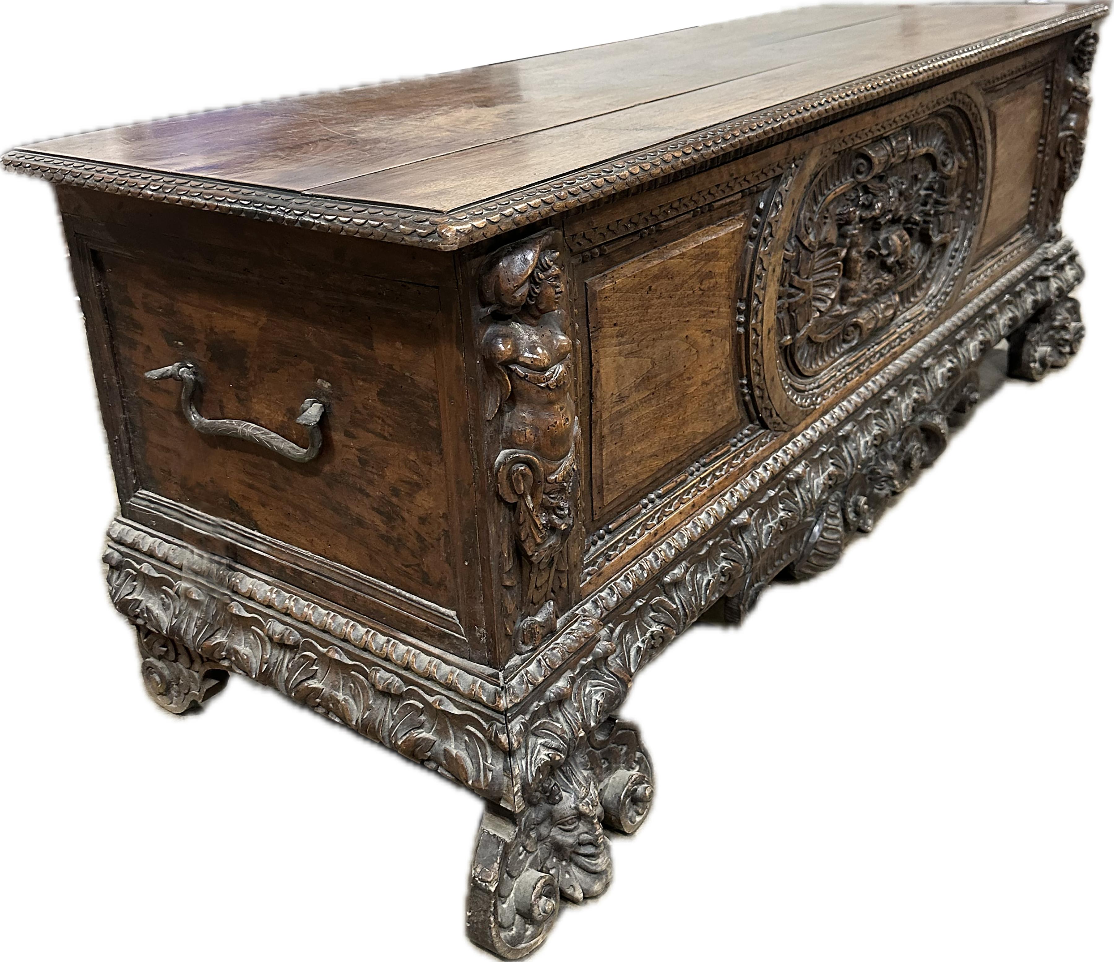 A handsome wide Italian walnut Cassone. Intricately carved gothic style narrative carvings on the front along the side, bottom, and center. Rich patinated burnt umber color wood finish. 17th century circa 1680. 
Provenance: Originally from Newport